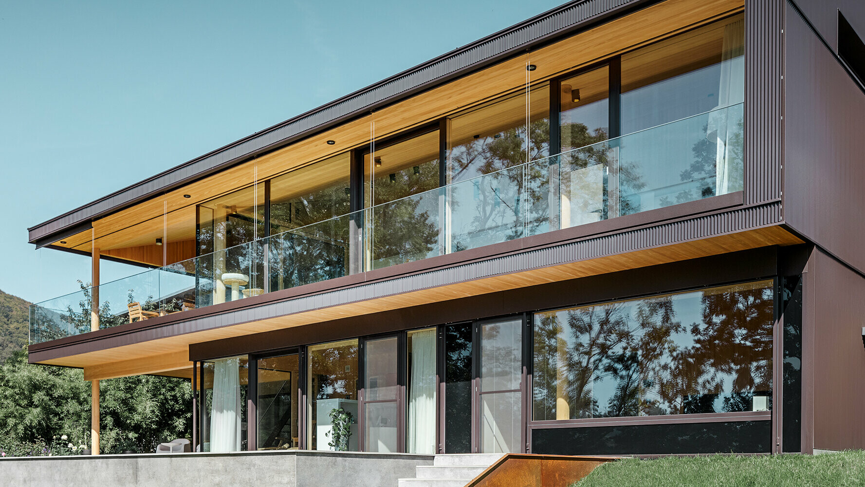 Nowy dom jednorodzinny z dużymi przeszkleniami i brązową aluminiową elewacją