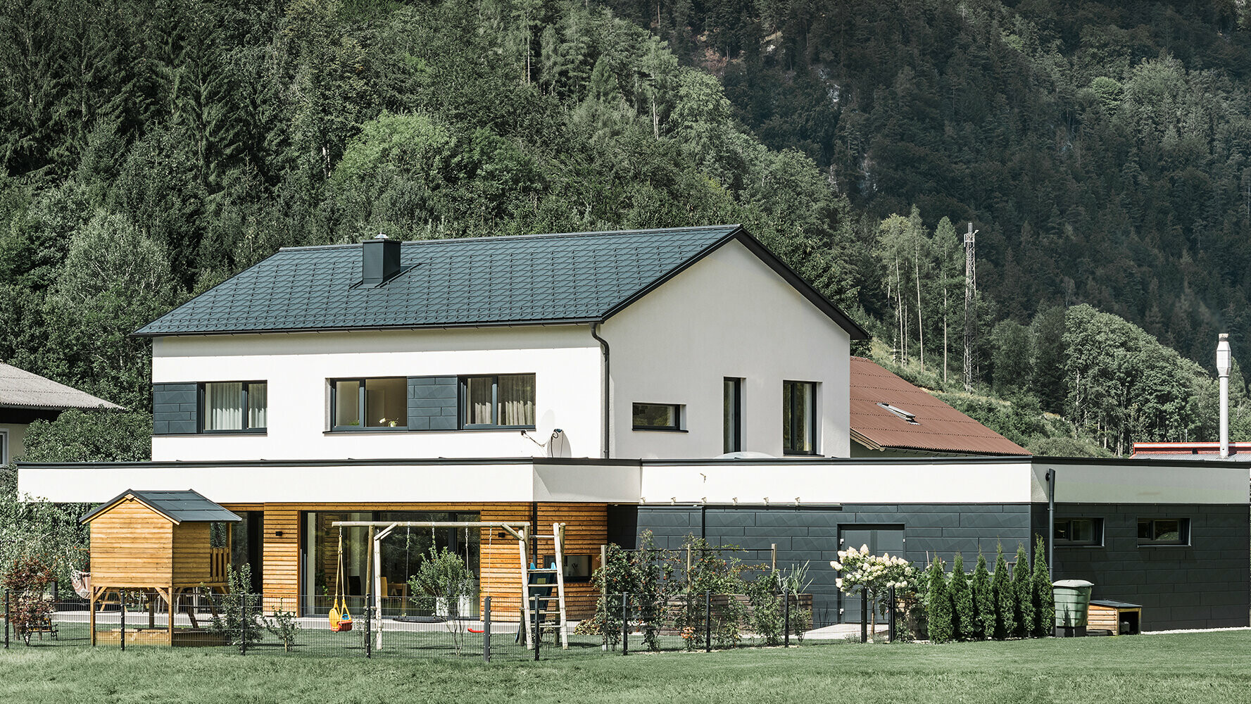 Nowy dom jednorodzinny z fasadą z drewna modrzewiowego w połączeniu z PREFA Siding.X w kolorze antracytowym.