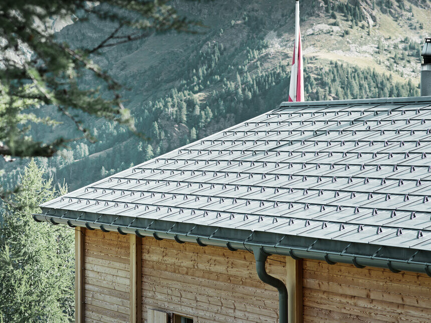 Szwajcarska chata pokryta jest dachówką klasyczną PREFA oraz wyposażona w rynnę półokrągłą PREFA, zamocowaną na wspornikach.