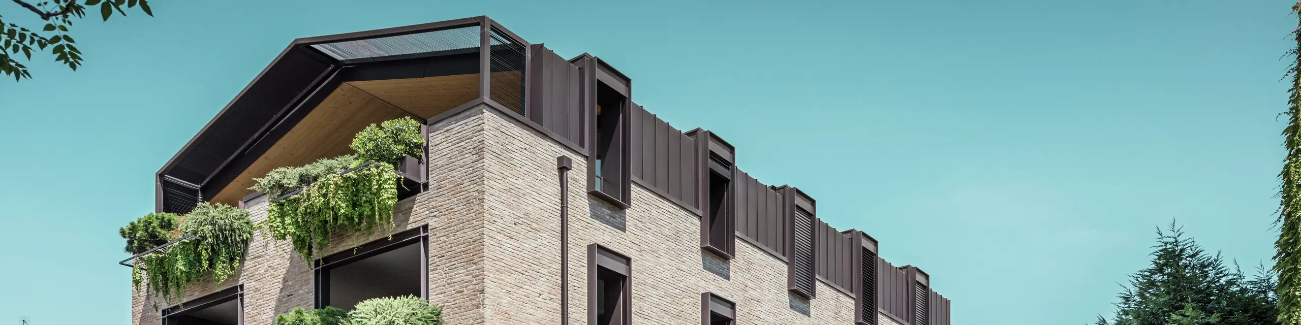 Nowoczesny budynek mieszkalny we Włoszech z dachem aluminiowym PREFALZ w kolorze P.10 orzechowym, fasadą z cegły i wiszącymi ogrodami – zrównoważona architektura przy renowacji tego budynku.