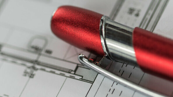 Czerwony długopis PREFA na planie projektowym. 