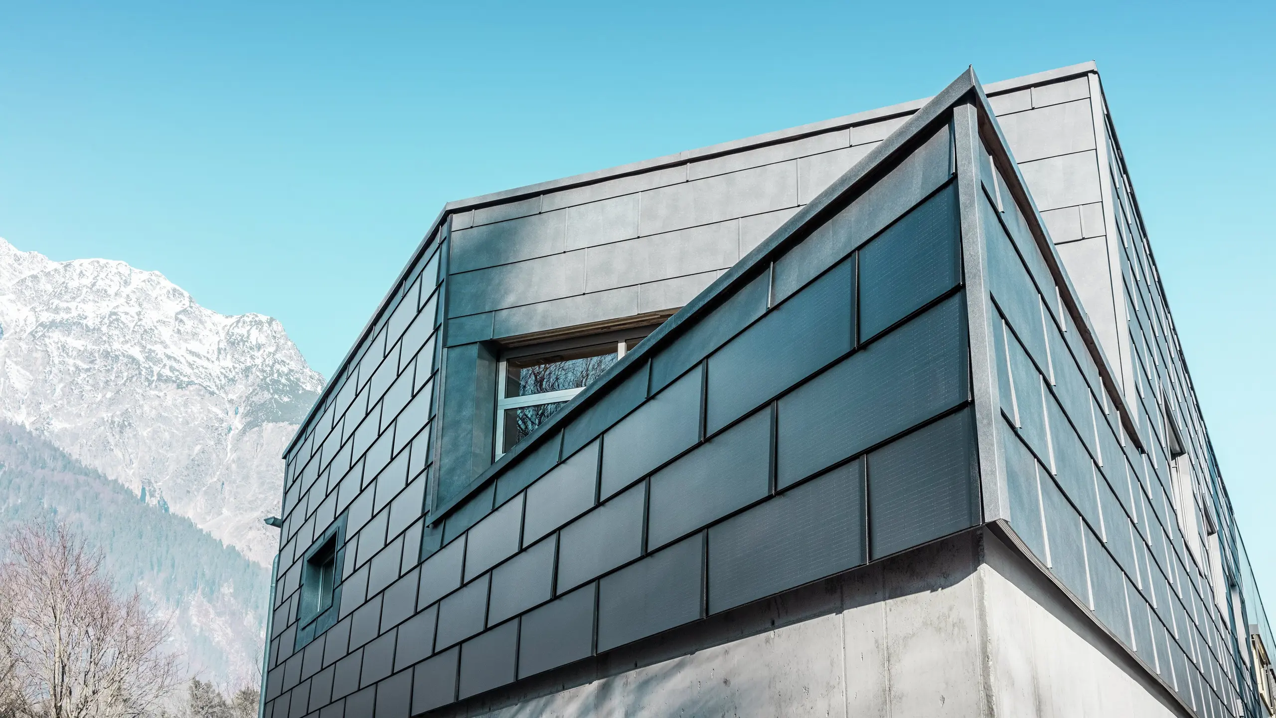 Nowoczesna elewacja z dachówką solarną PREFA: ekologiczne płyty aluminiowe z wbudowanym systemem fotowoltaicznym wytwarzają energię elektryczną i harmonijnie komponują się z architekturą budynku.