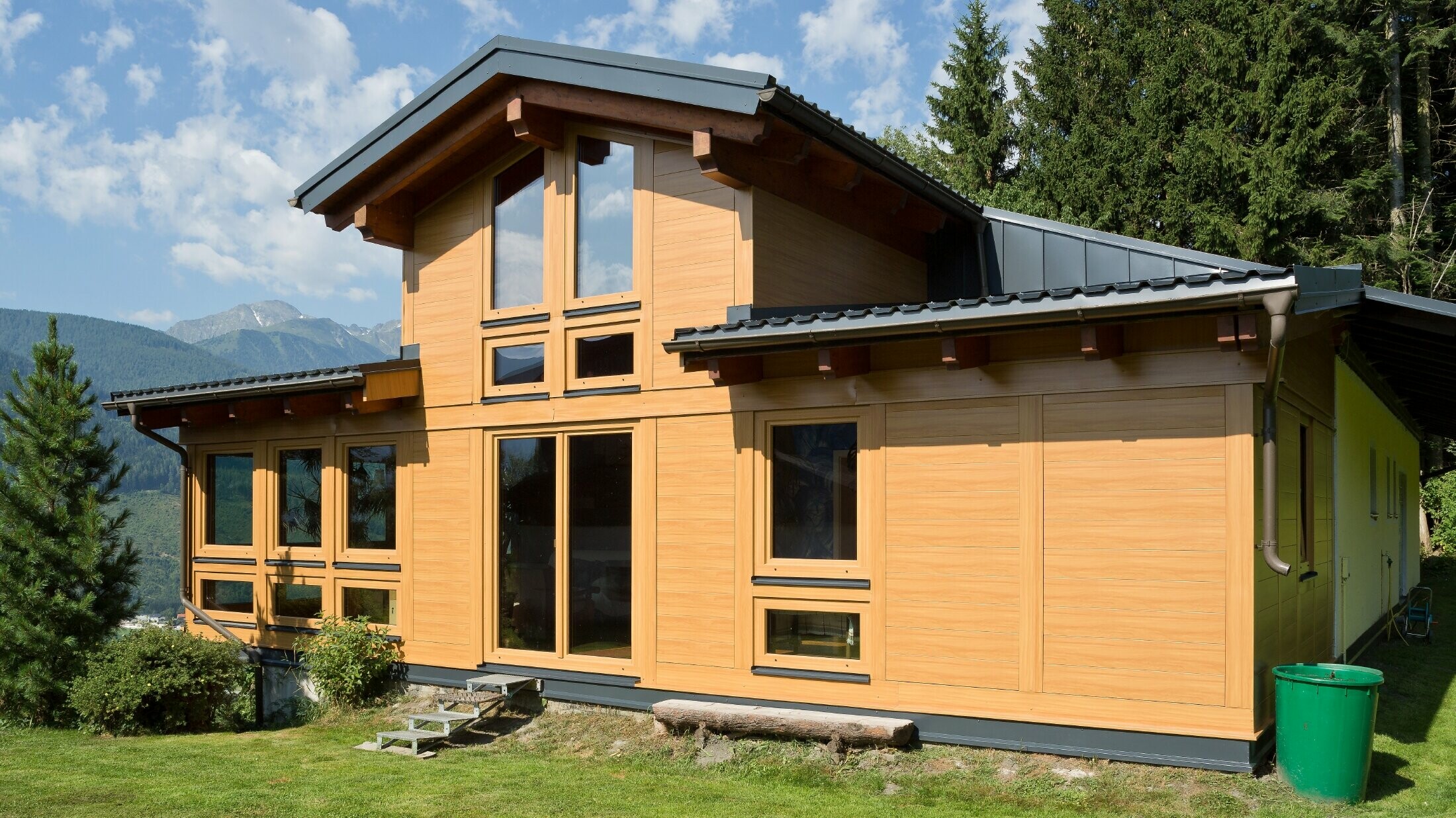 Przybudówka ogrodu zimowego z okładziną elewacyjną PREFA — sidingi aluminiowe w kolorze jasnego drewna.