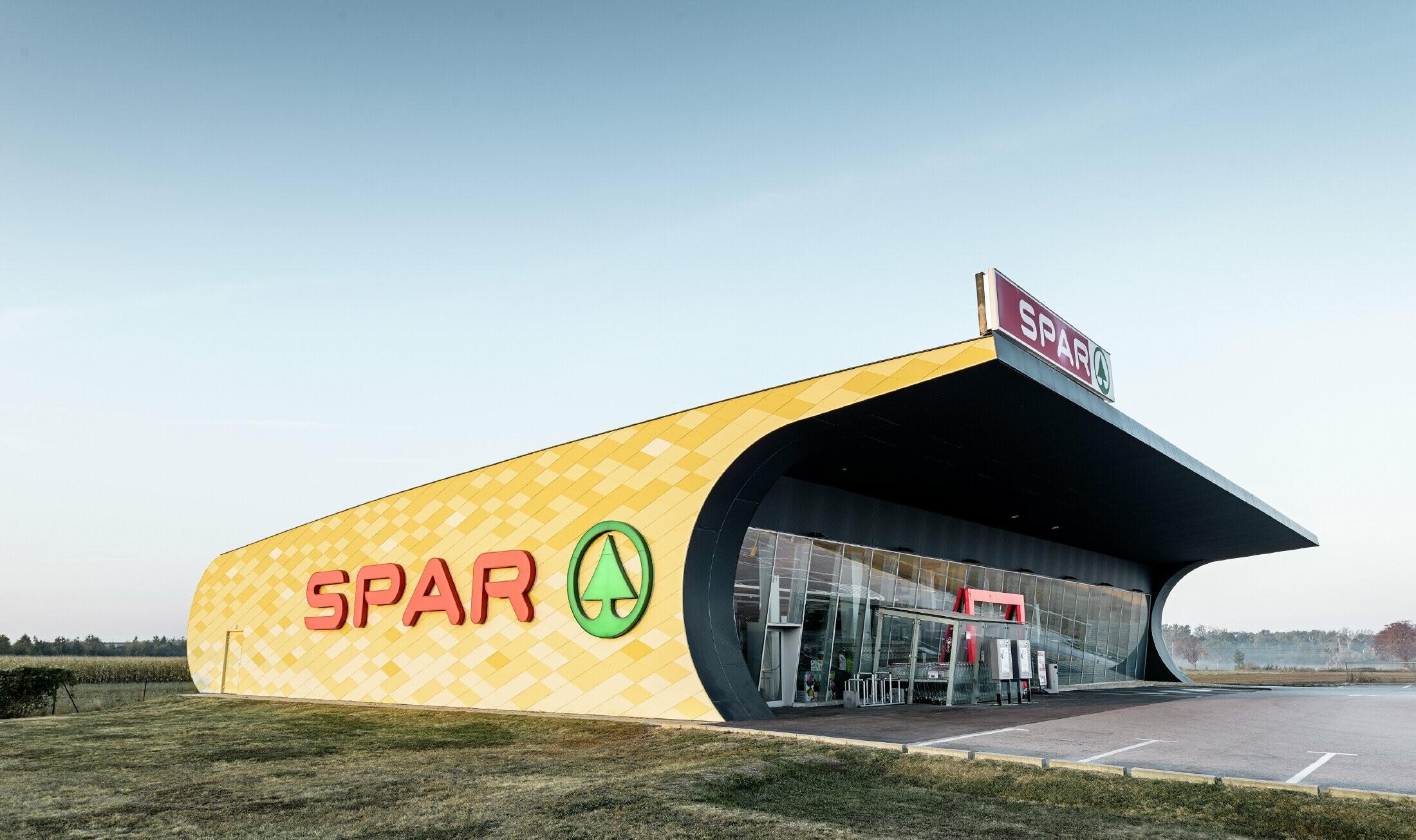 Filia banku Spar z elewacją aluminiową z pomarańczowo-żółtych rombów i z logo Spar
