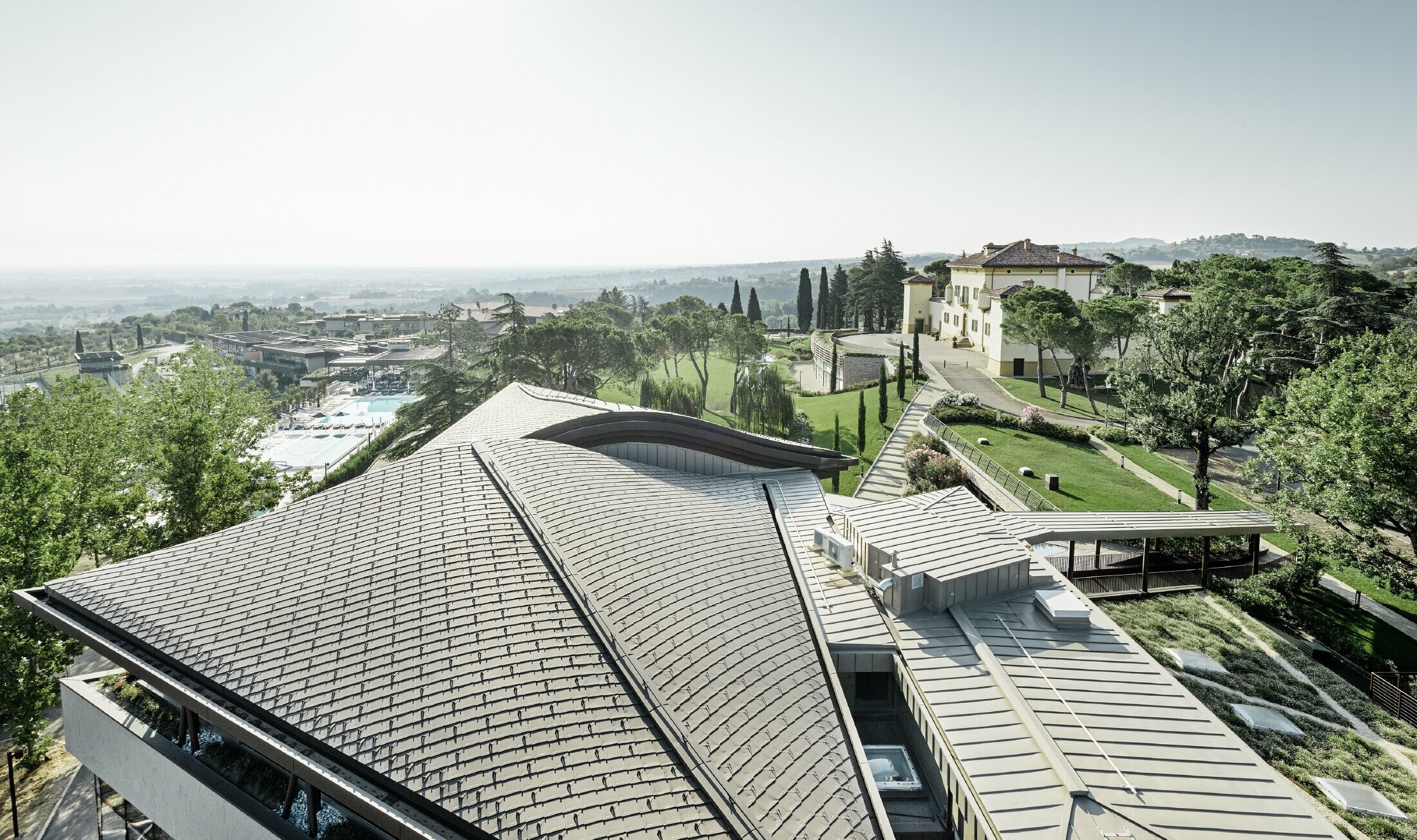 Palazzo w ośrodku golfowym Varignana z rozległym dachem aluminiowym PREFA w kolorze brązowym