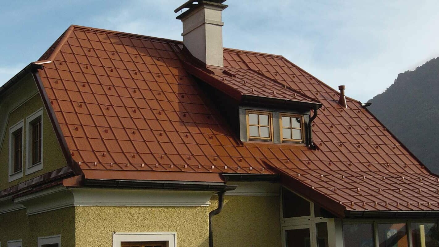 Dom jednorodzinny z dachem naczółkowym i oknem dachowym ze zmodernizowanym dachem z płytą dachową PREFA w kolorze ceglastym