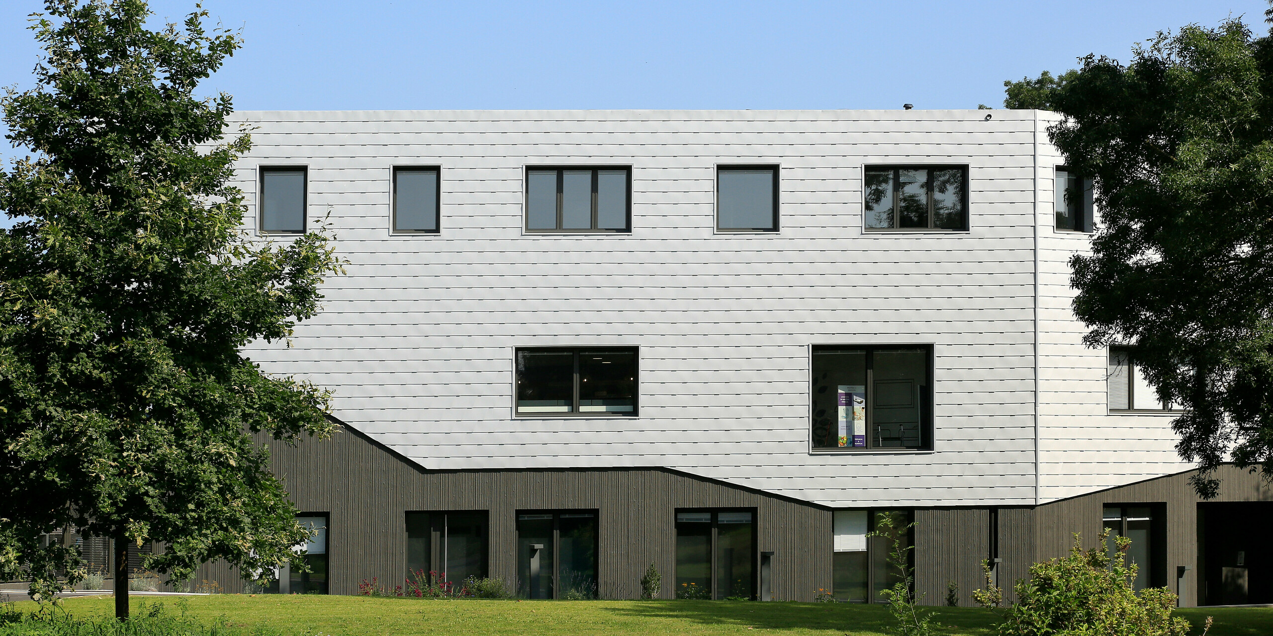 Gartenseite zur silberschimmernden Aluminiumhülle des Gesundheitszentrums in Le Laandreau