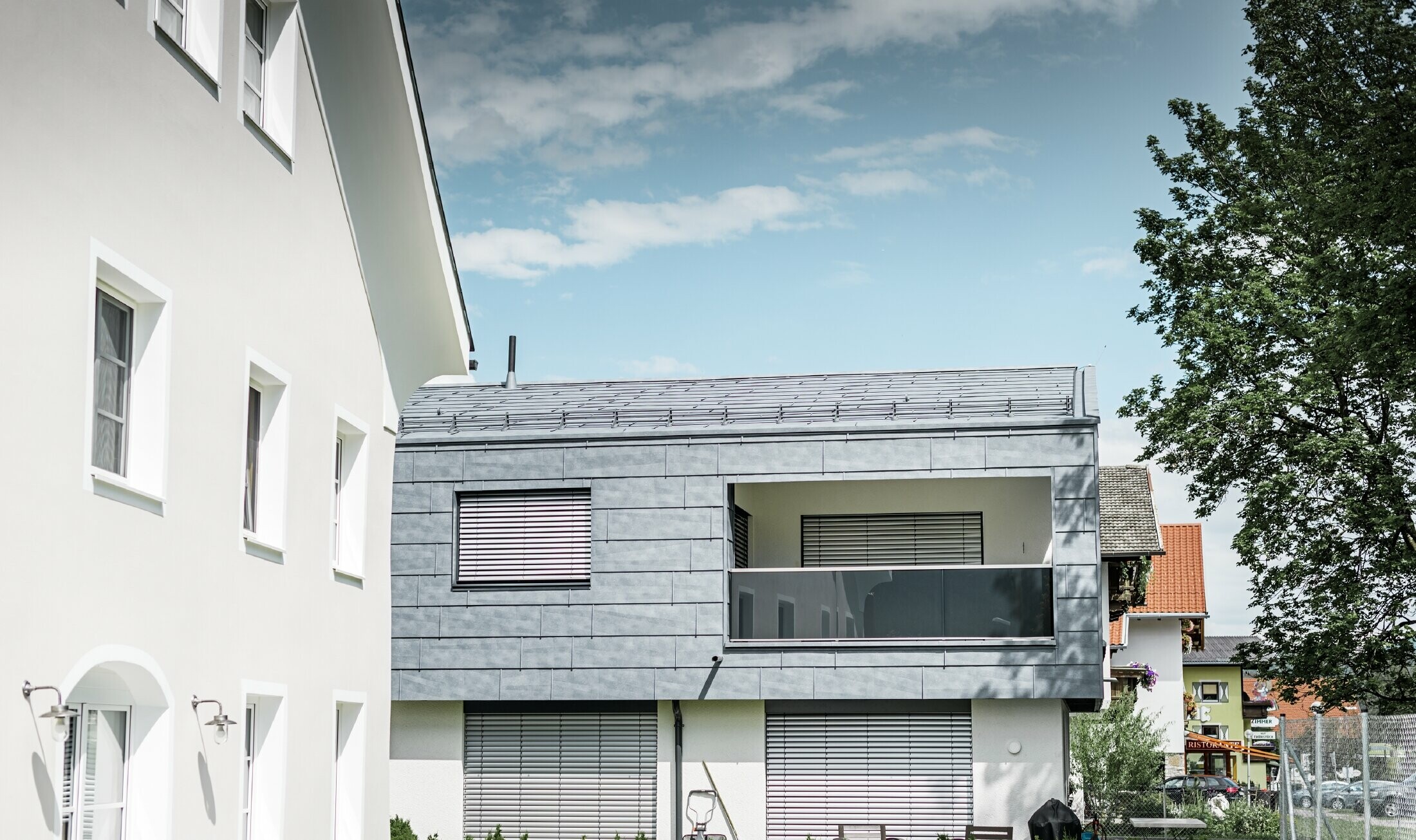 Całą górną część tego domu mieszkalnego w Mieming obłożono panelem elewacyjnym FX.12 PREFA w kolorze szarym kamiennym.