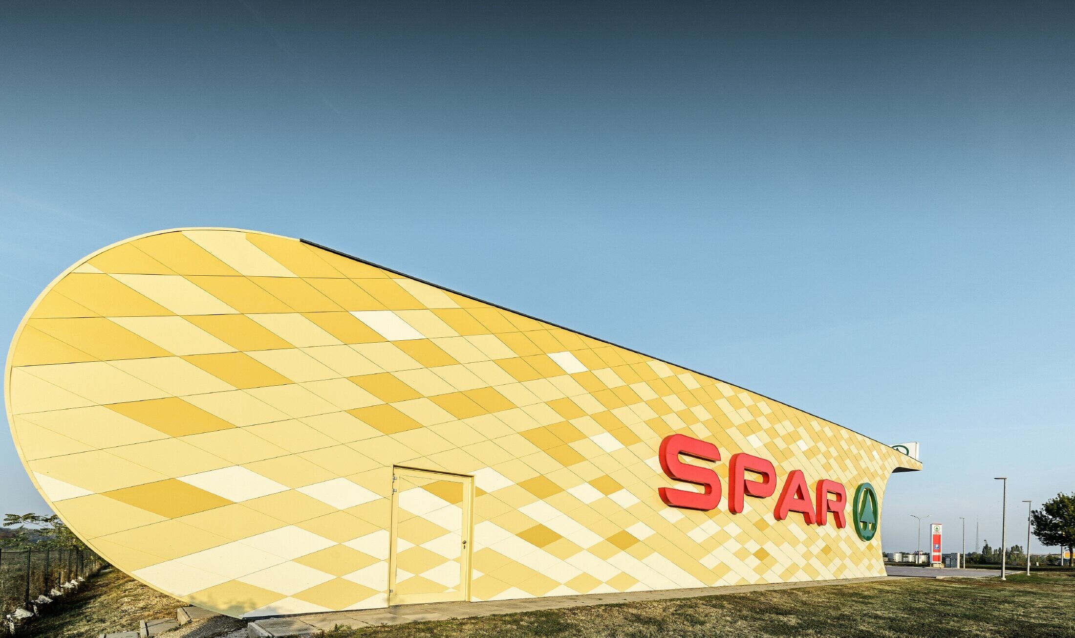 Filia banku Spar z elewacją aluminiową z pomarańczowo-żółtych rombów i z logo Spar