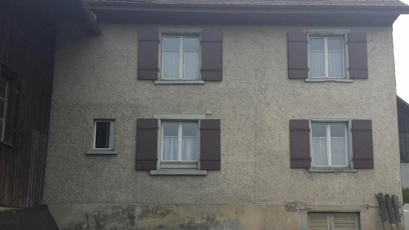 Dom przed modernizacją elewacji z płytami ściennymi rombowymi PREFA, okno z czerwonymi okiennicami