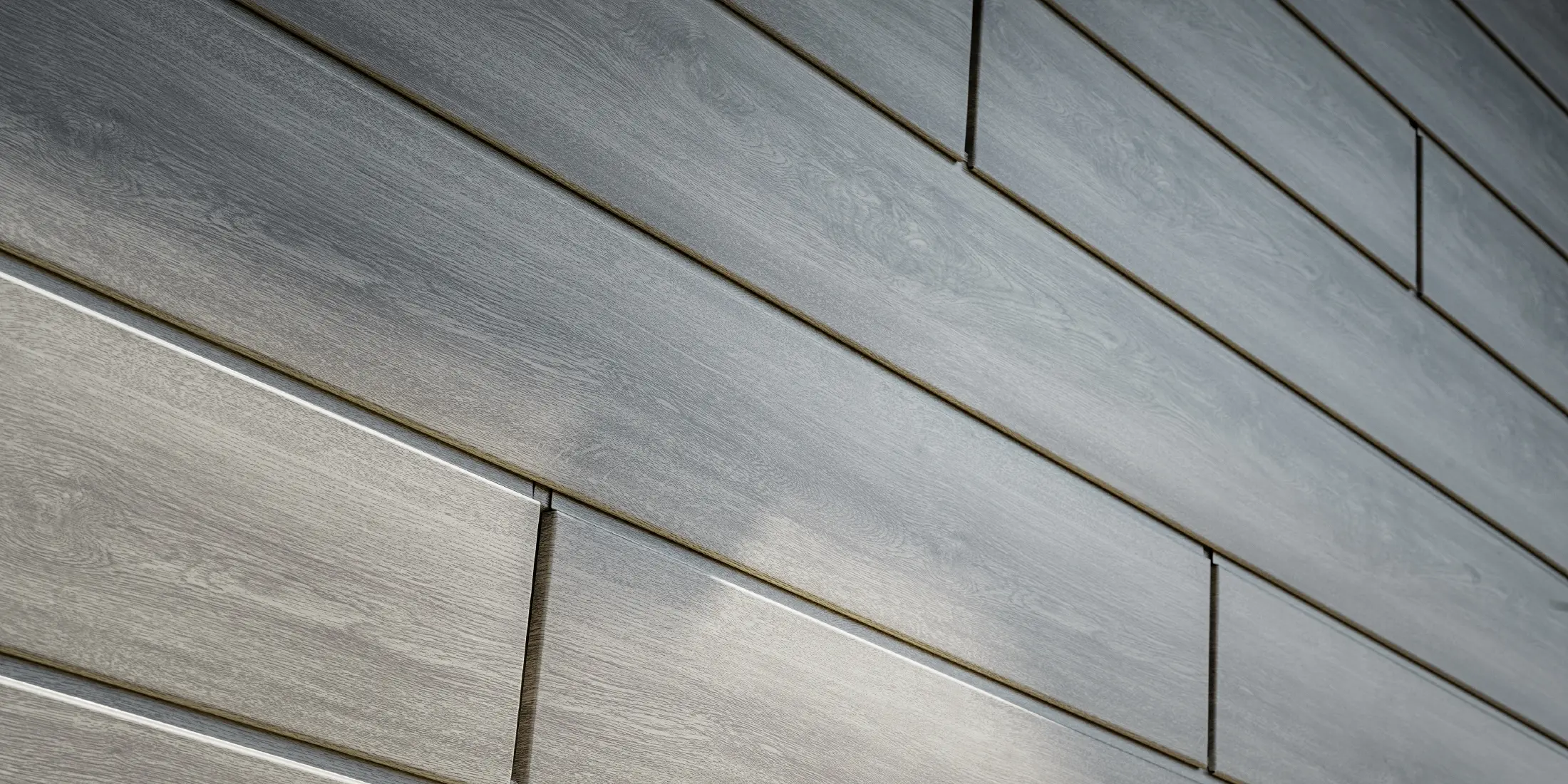 Zbliżenie na elewację aluminiową PREFA Siding. Panele aluminiowe zostały ułożone poziomo i mają wygląd drewna – dąb szary.