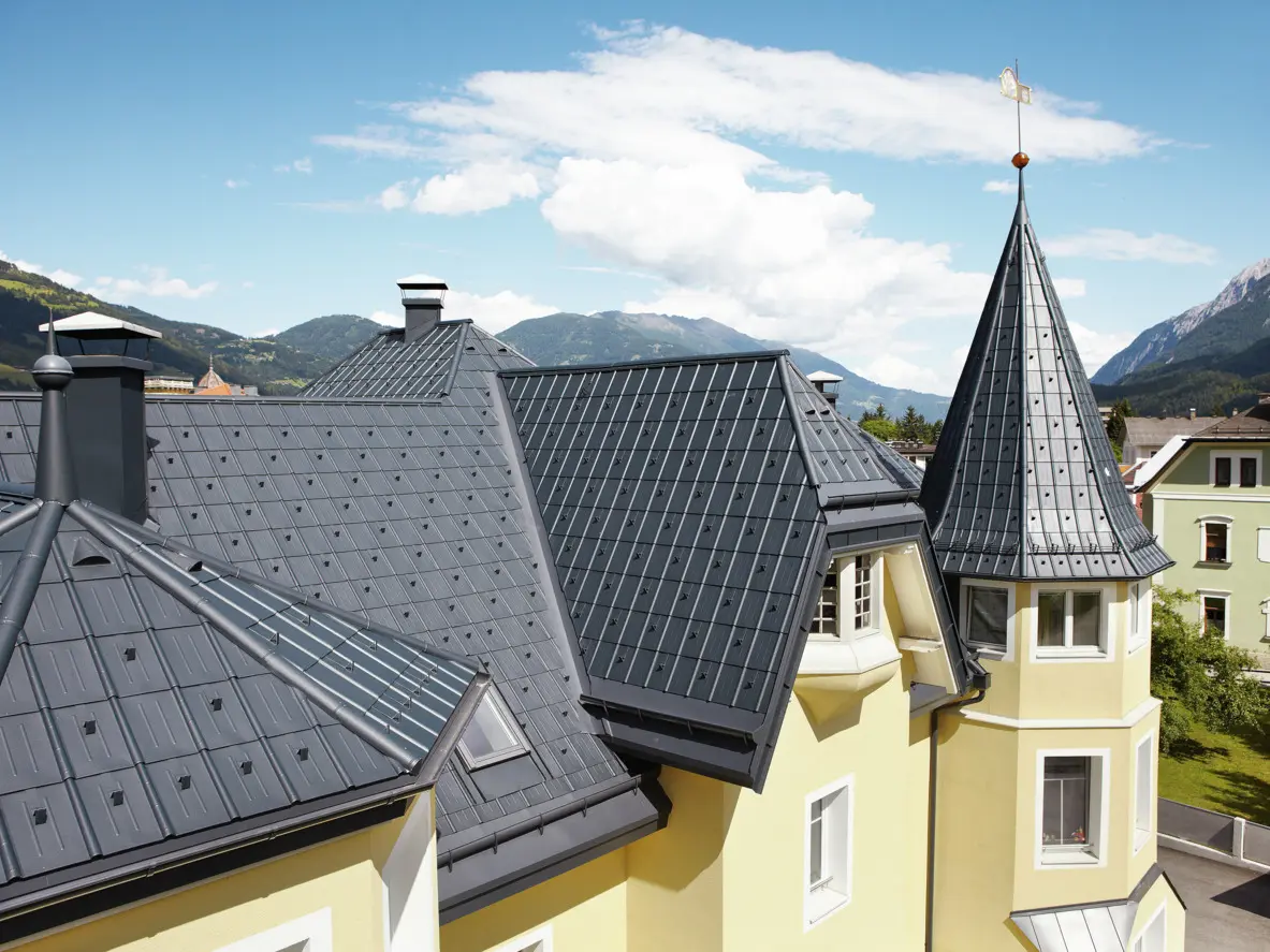 W budynkach z licznymi szczegółami architektonicznymi, wieżyczkami i kątowymi połaciami dachowymi dach pokryto Dachówką klasyczną PREFA. Przy odwodnieniu dachu stosuje się rynnę półokrągłą PREFA oraz rynnę leżącą PREFA w kolorze antracyt.