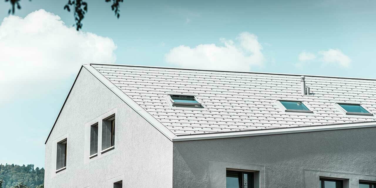 Dom wielorodzinny z ukośną rynną i białym panelem dachowym PREFA FX.12.