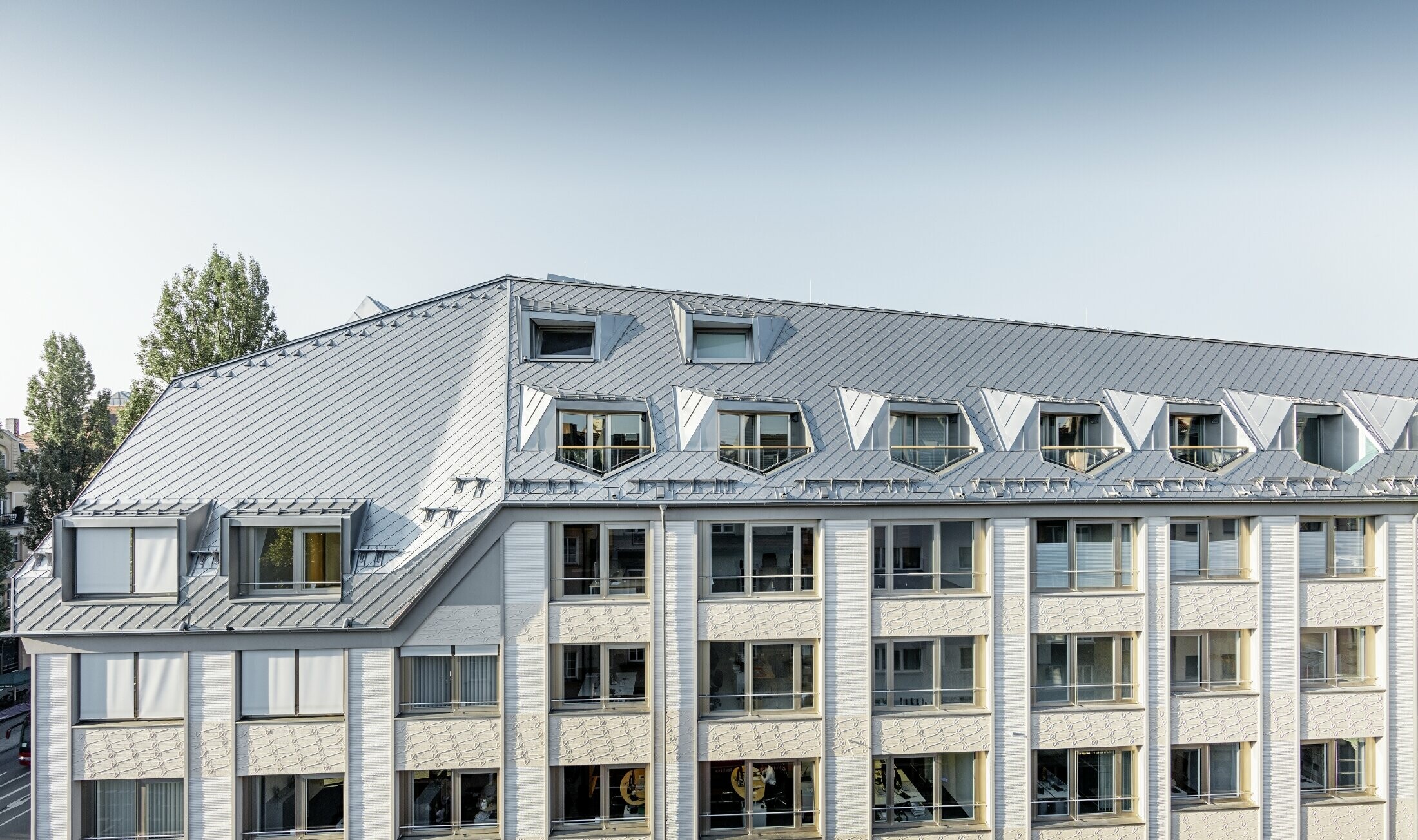 Zrewitalizowane mieszkania mansardowe z obszernymi, otwartymi galeriami, mieszczące się w budynku mieszkalno-biurowym przy skrzyżowaniu ulic Leopoldstraße/Hohenzollernstraße w Monachium, z pokryciem dachowym wykonanym z dachówki romb PREFA