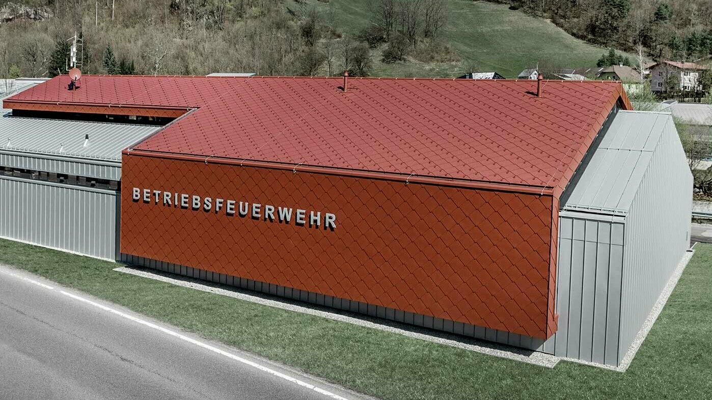 Nowy budynek zakładowej straży pożarnej firm PREFA i Neuman Aluminium został obłożony nowymi dachówkami rombowymi i rombowymi płytami ściennymi 44 x 44 w kolorze P.10 czerwony tlenkowy i blachą Prefalz w kolorze srebrny metallic.