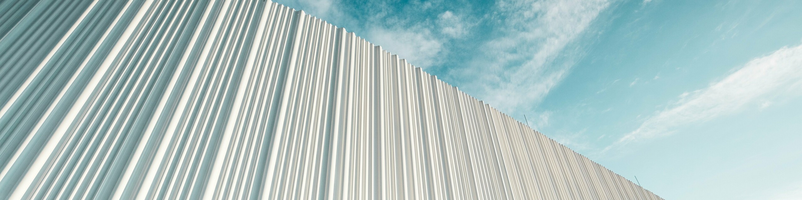 Oszałamiająca architektura z białą elewacją aluminiową PREFA w Walter Business Park pod Wiedniem. Elewacja wykonana z indywidualnie dopasowanych profili tworzy fascynującą grę światła i cienia dzięki płynnym falistym kształtom. Trzy różne kształty profili zapewniają niezwykły efekt głębi i nadają budynkowi stylowy, a jednocześnie dynamiczny wygląd. Trwała, odporna na warunki atmosferyczne powierzchnia PREFA łączy w sobie nowoczesną estetykę z funkcjonalną perfekcją – to prawdziwa atrakcja współczesnego projektowania fasad, która uwidacznia jakość architektoniczną i techniczną wyrafinowanie.