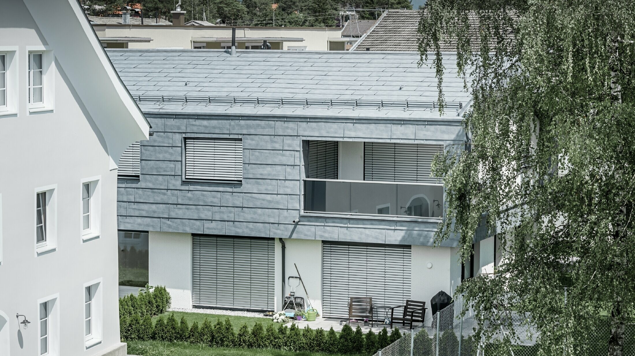 Klasyczny dom jednorodzinny z dachem szczytowym z dwoma oknami dachowymi, kryty panelem dachowym PREFA FX.12 w kolorze szarym kamiennym.