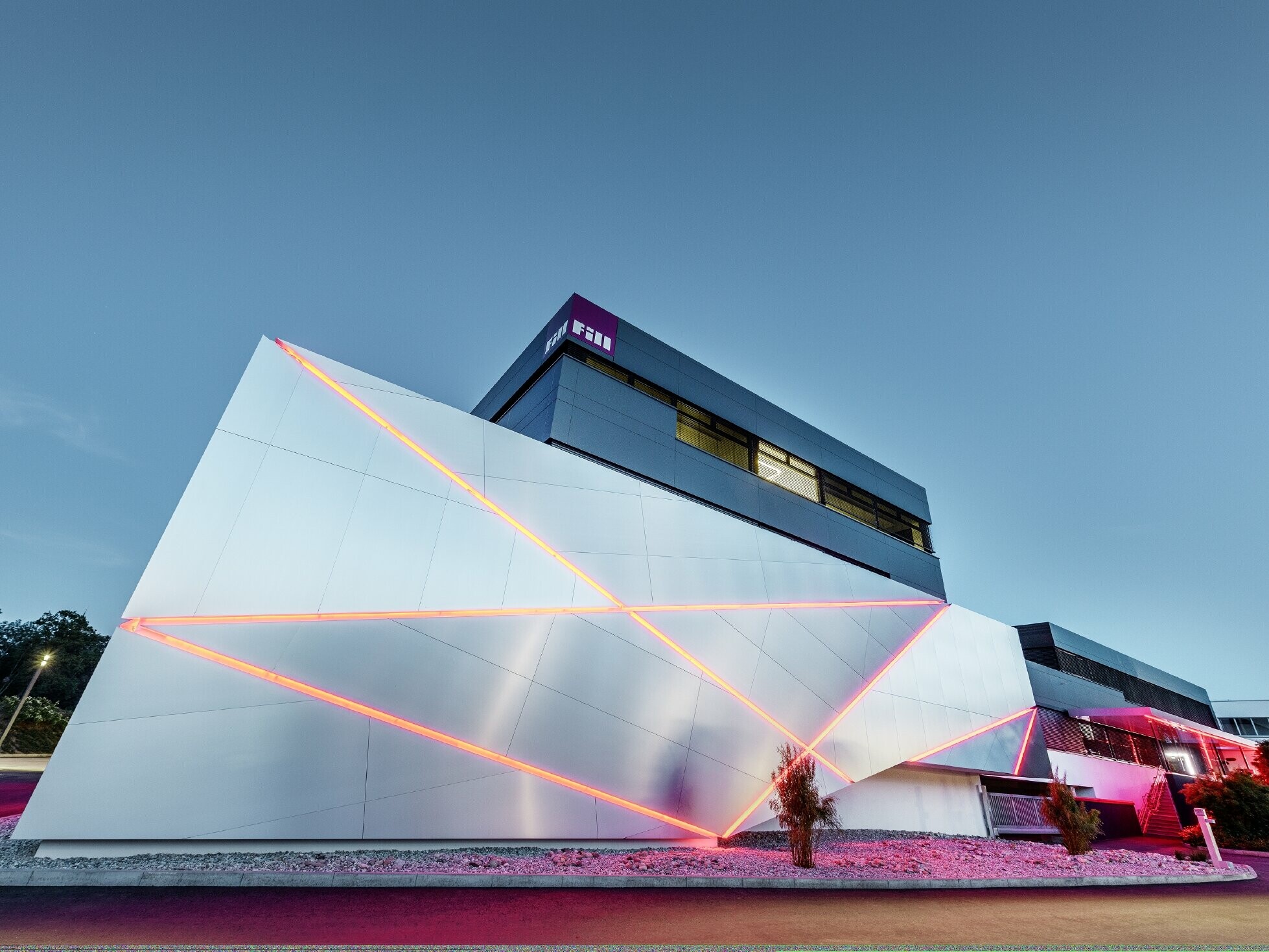 Budynek firmy Fill z futurystyczną elewacją z płyty kompozytowej wykonanej ze szczotkowanego aluminium i z podświetlanymi spoinami