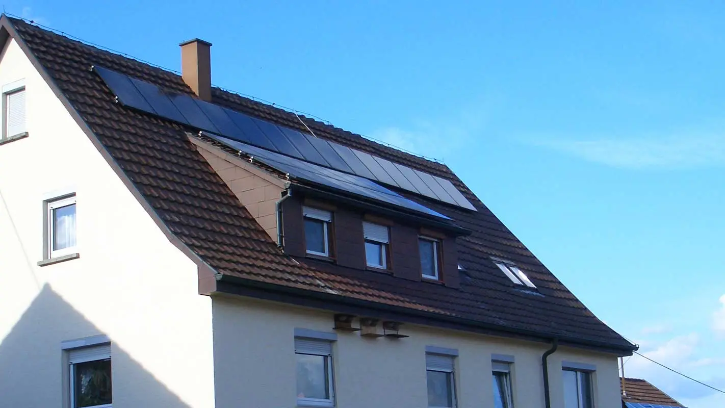 Dom jednorodzinny z wymagającą modernizacji dachówką; na dachu znajduje się okno dachowe i instalacja fotowoltaiczna.