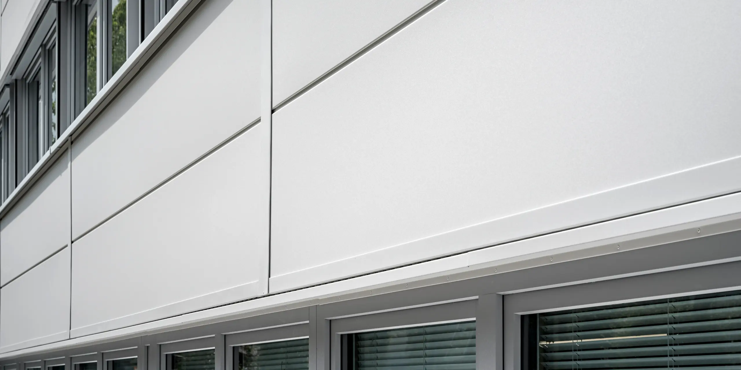 Großformatige PREFA Sidings umhüllen ein Firmengebäude in Oberschleißheim (Deutschland). Die extrabreiten Fassadenelemente aus Aluminium sind in der Farbe Prefaweiß gehalten.