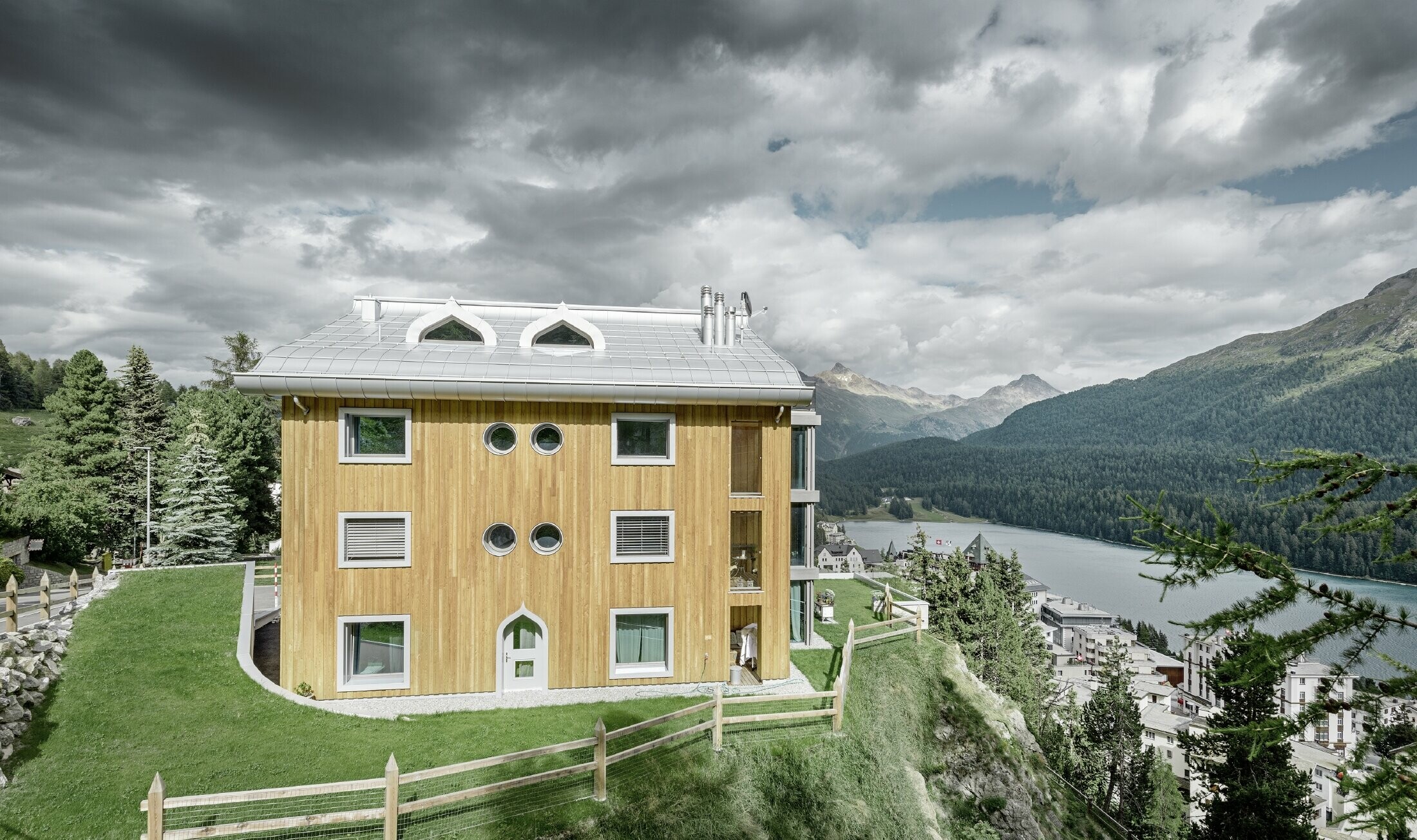 Osiedle mieszkaniowe w St. Moritz z drewnianą elewacją i dachem aluminiowym z łukowatym okapem w kolorze srebrny metallic