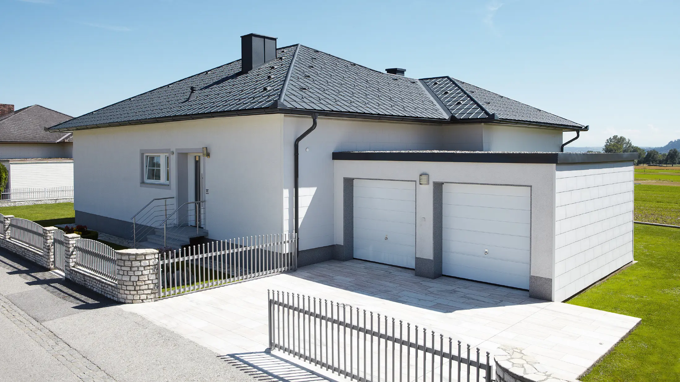 Nowo wybudowany bungalow z dachem namiotowym został pokryty dachówka klasyczna PREFA w kolorze P.10 antracyt. Podwójny garaż został dodany po prawej stronie, sfotografowany od ulicy.