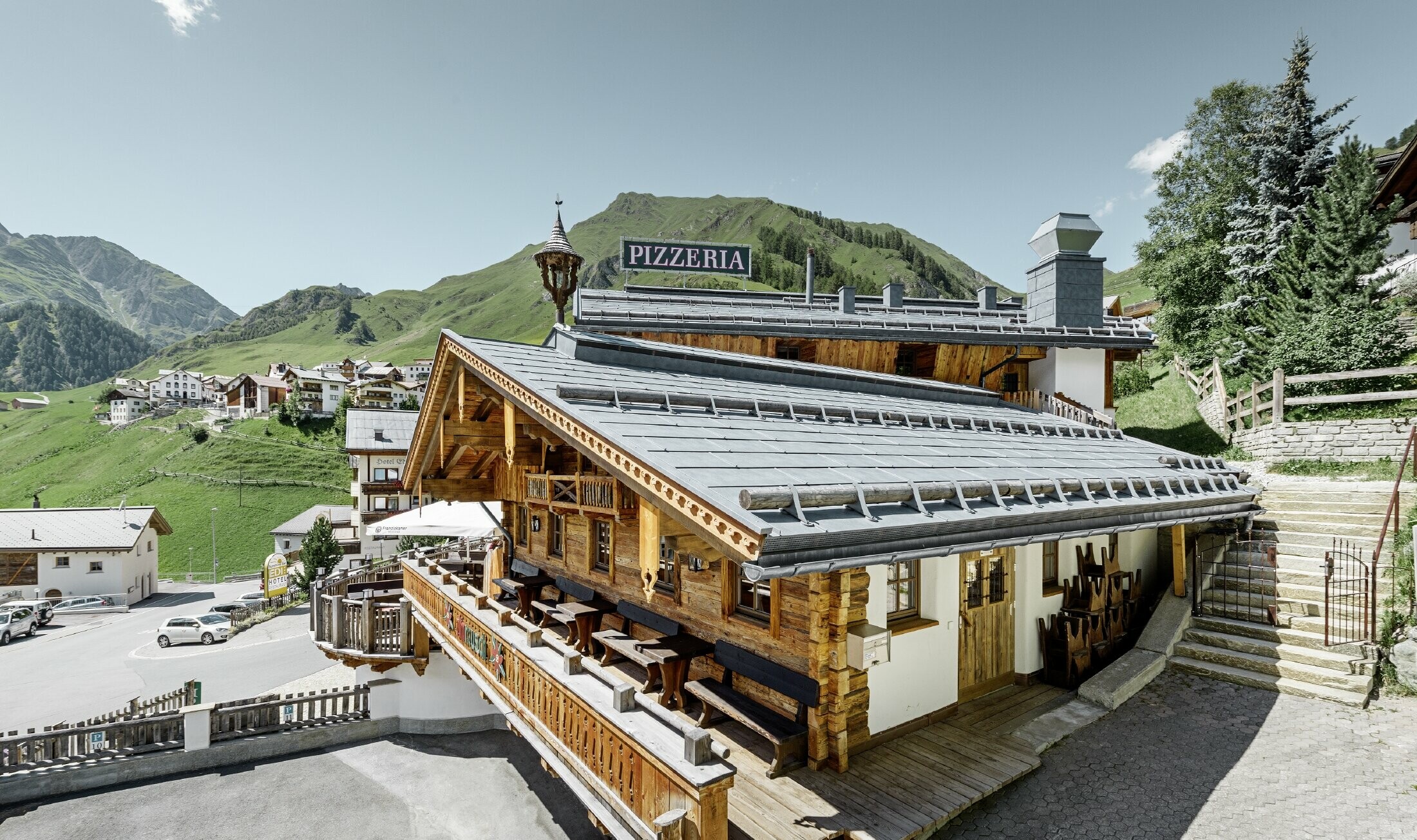 Restauracja Almrausch z górami w tle, na dachu panele dachowe PREFA FX.12 w kolorze kamiennym szarym ze śniegołapami