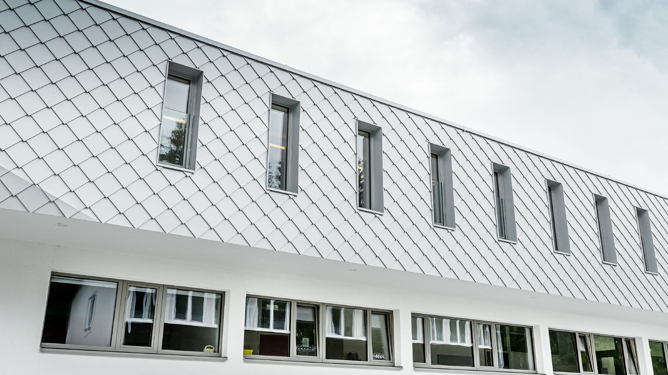 Nowo wybudowane przedszkole w Kaprun z nowoczesną aluminiową elewacją wykonaną z rombu fasadowego PREFA w kolorze bieli prefa