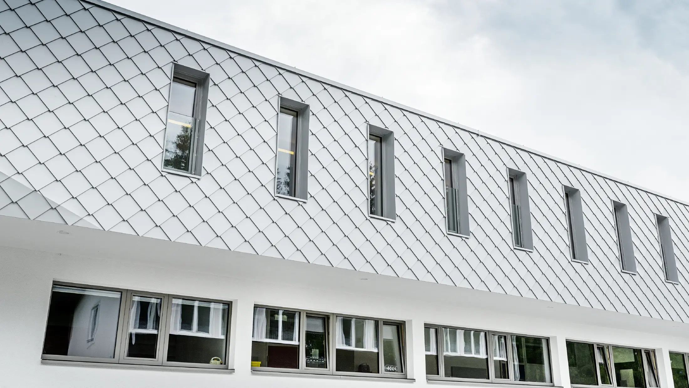 Nowo wybudowane przedszkole w Kaprun z nowoczesną aluminiową elewacją wykonaną z rombu fasadowego PREFA w kolorze bieli prefa