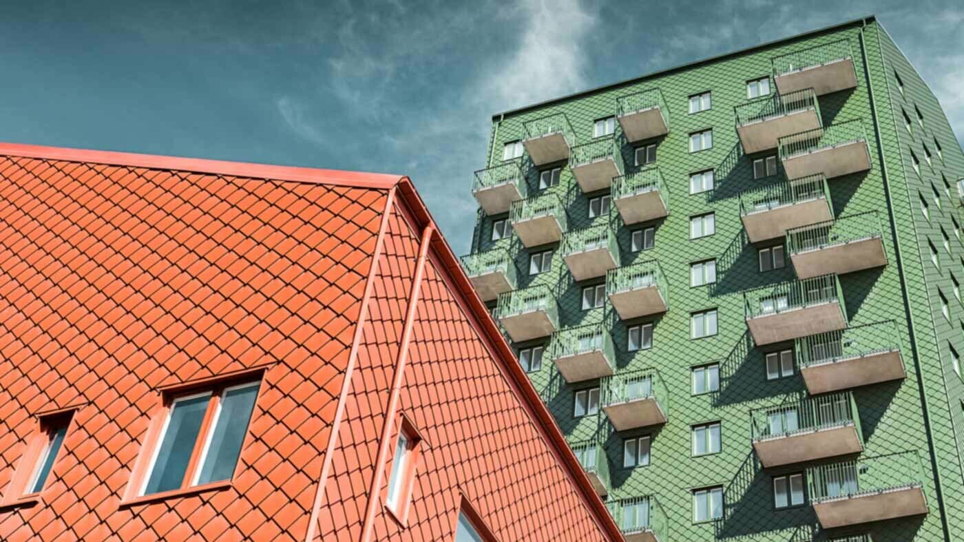 Szwedzkie domy mieszkalne z balkonami i rombową płytą ścienną PREFA w kolorze zielonym i ceglastym.