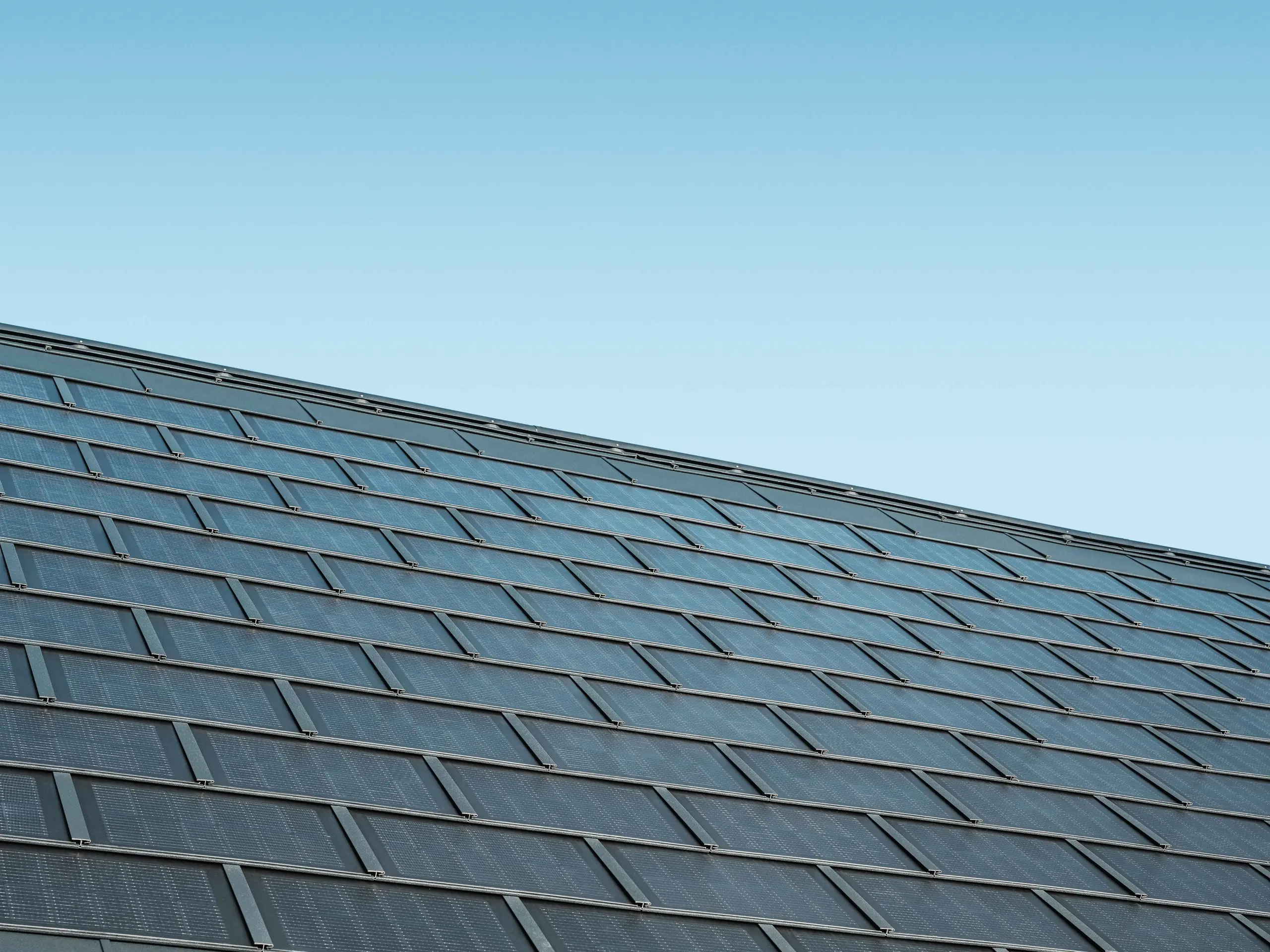Zdjęcie ułożonej połaci z dachówka solarna w kolorze antracytowym w połączeniu z dachówką klasyczną R.16