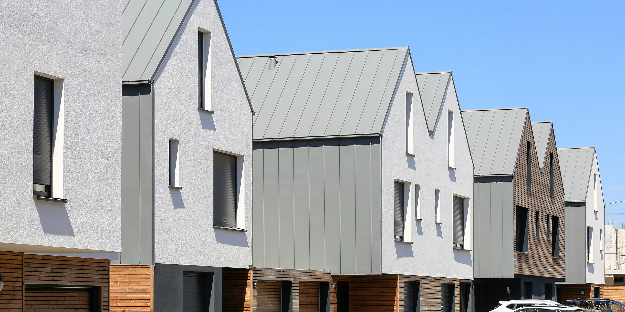 PREFALZ in Hellgrau zieht sich über die Fassaden und Satteldächer einer Reihenhaus-Siedlung in Mundolsheim. Die einheitlichen Gebäudehüllen aus Aluminium schaffen ein harmonisches Gesamtbild.