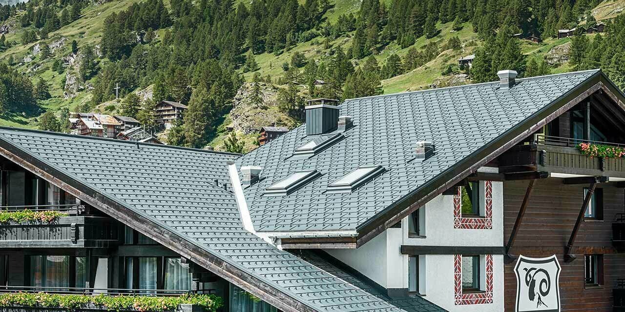 Hotel Alpenhof w Zermatt ze szczytem Matterhorn w tle, balkony, ciemna elewacja drewniana i aluminiowy dach PREFA w kolorze antracytu