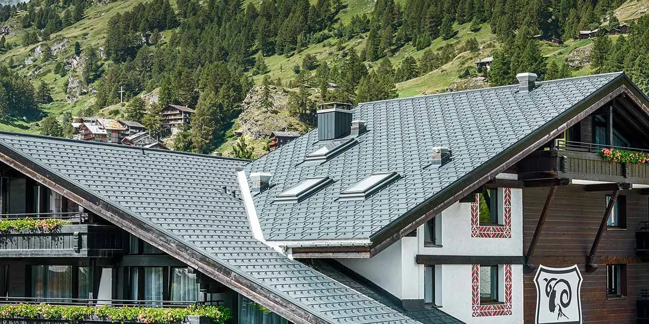 Hotel Alpenhof w Zermatt ze szczytem Matterhorn w tle, balkony, ciemna elewacja drewniana i aluminiowy dach PREFA w kolorze antracytu