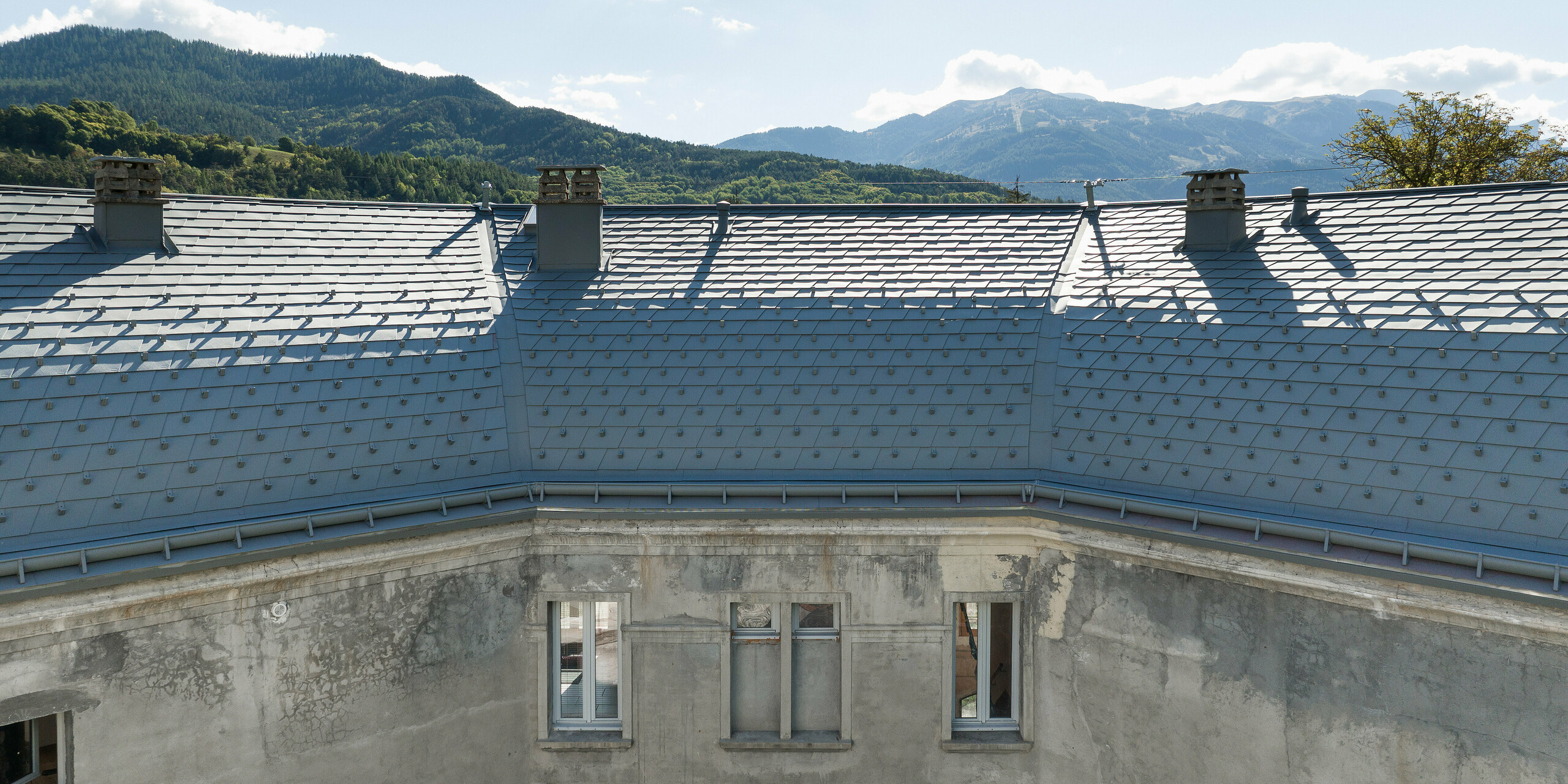 Die großflächige Dachlandschaft eines Anwesens in Barcelonnette, Frankreich wurde mit der PREFA Dachschindel in P.10 Hellgrau saniert. 