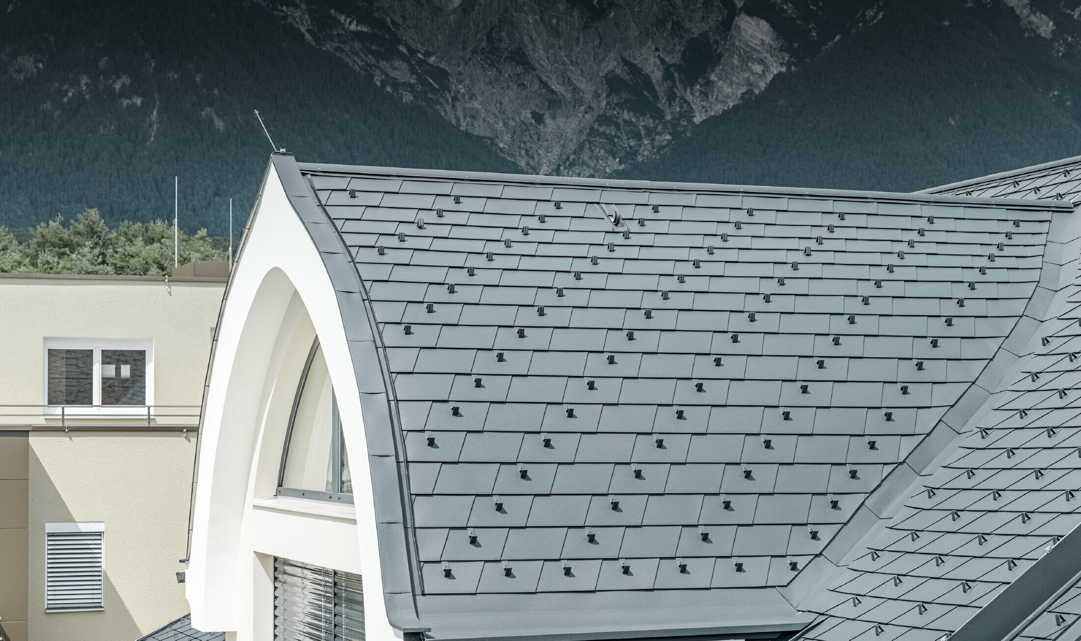 Detal opływowej lukarny, krytej dachówką łupkową PREFA w kolorze antracytowym. Lukarna została wykonana w formie dachu owalnego.