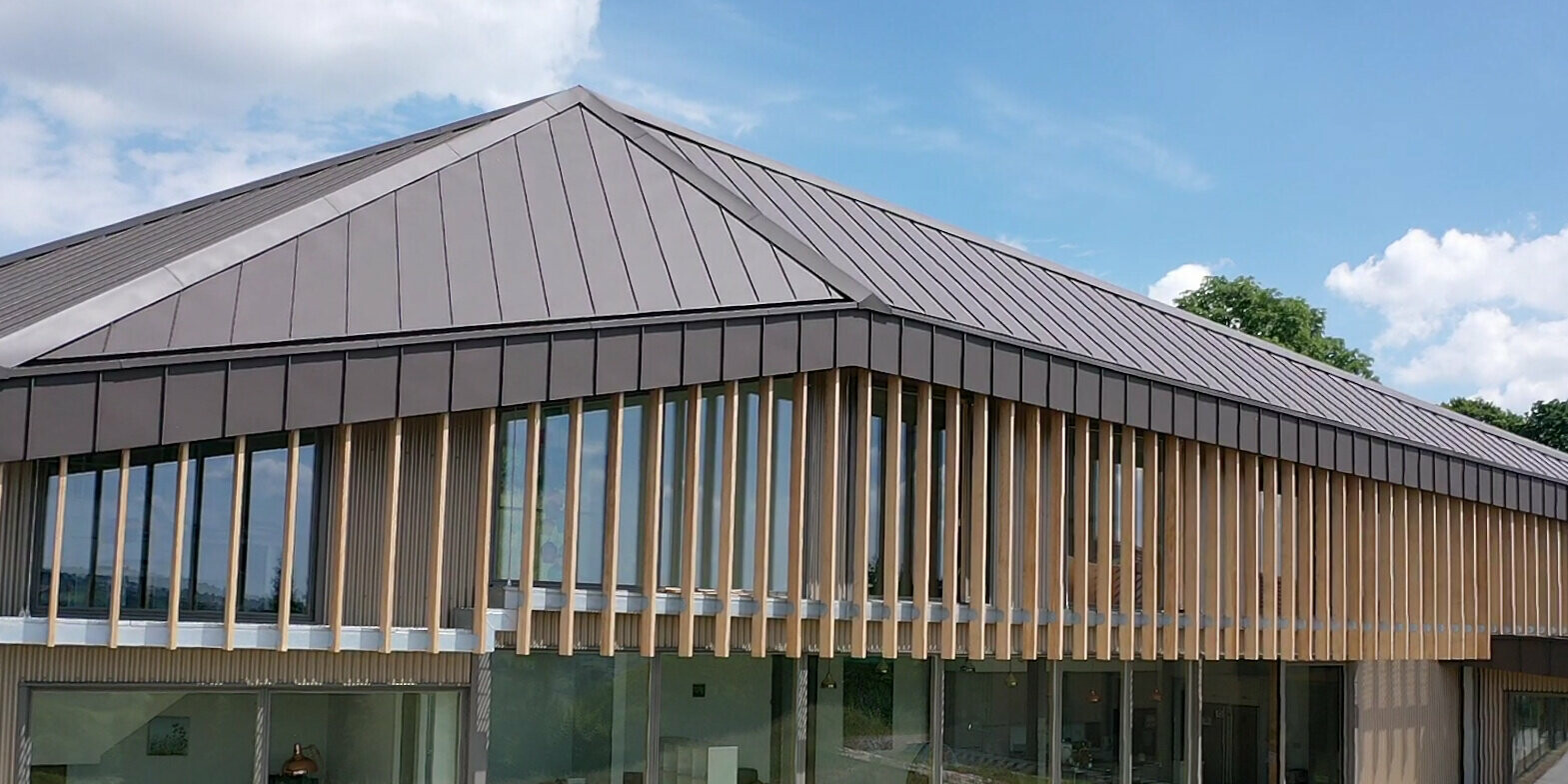 Nahaufnahme von einem Langhaus mit PREFA Aluminiumdach und Fassade aus einzelnen Holzelementen