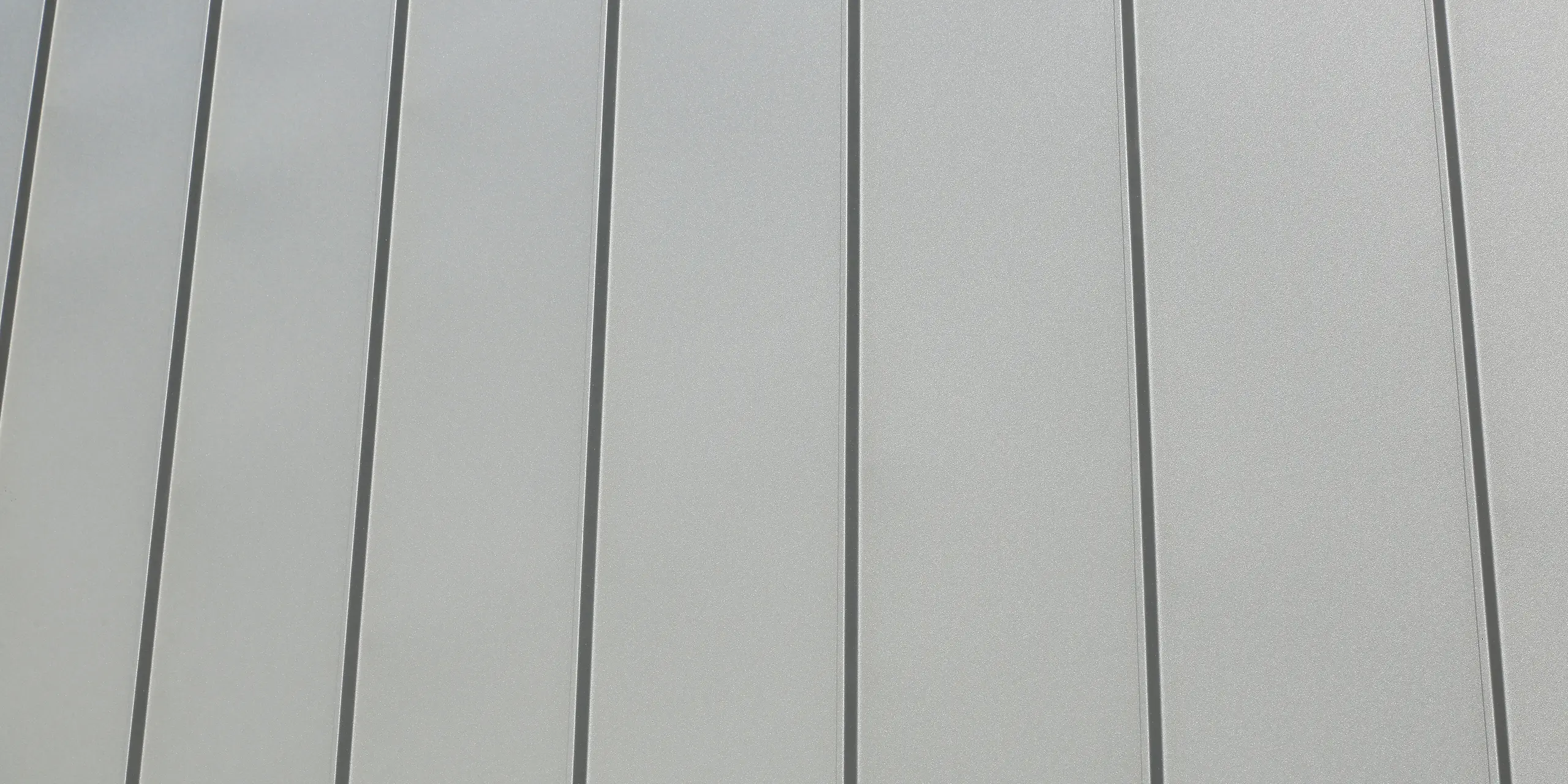 PREFALZ in Hellgrau zieht sich über die Fassaden und Satteldächer einer Reihenhaus-Siedlung in Mundolsheim. Die einheitlichen Gebäudehüllen aus Aluminium schaffen ein harmonisches Gesamtbild.