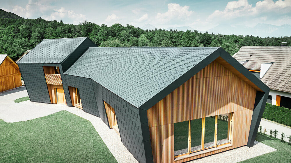 Duże powierzchnie dachu i elewacji pokryte dachówką łupkową DS.19 w kolorze antracytowym P.10, od frontu elewacja została pokryta drewnem