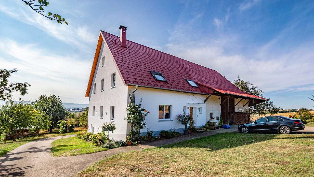 Stara wiejska chata ładnie wyremontowana za pomocą dachówki klasycznej PREFA w kolorze czerwonym tlenkowym.