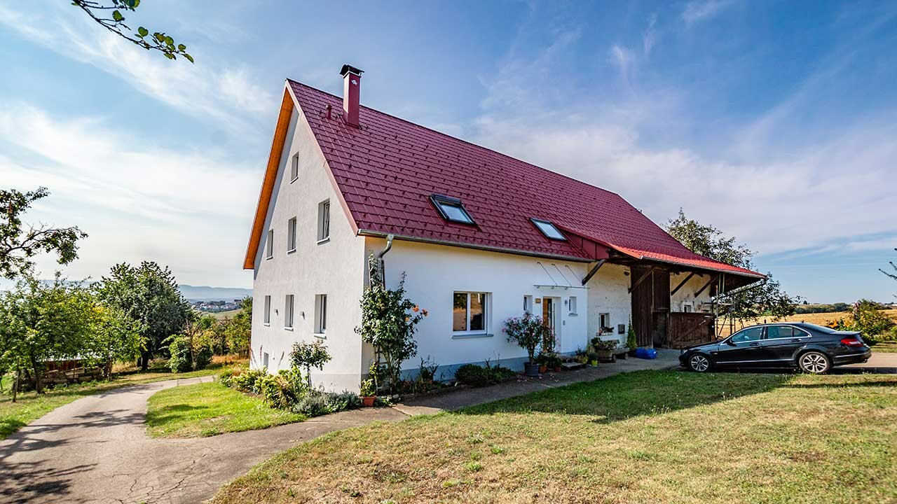 Stara wiejska chata ładnie wyremontowana za pomocą dachówki klasycznej PREFA w kolorze czerwonym tlenkowym.