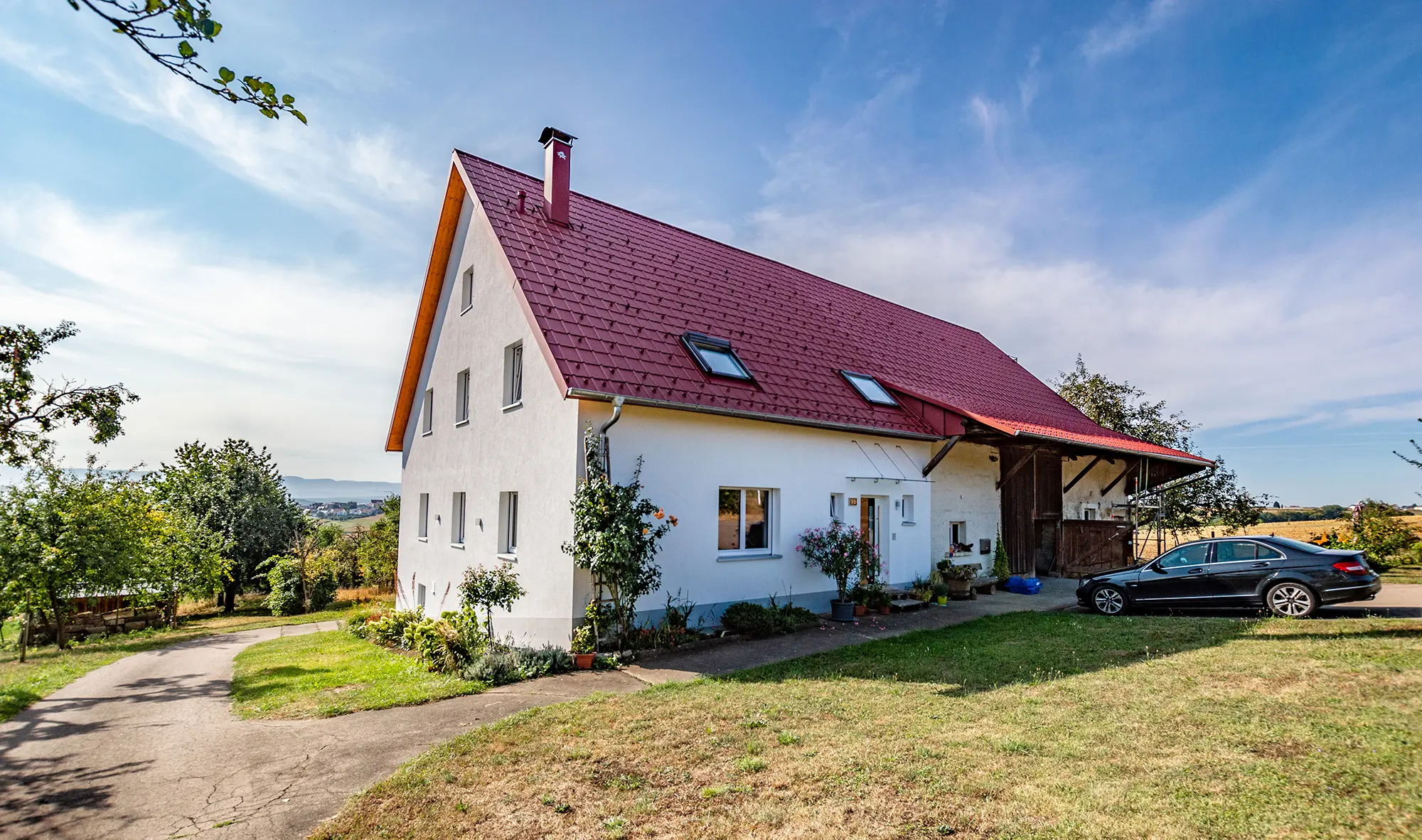 Stara wiejska chata ładnie wyremontowana za pomocą dachówki klasycznej PREFA w kolorze czerwonym tlenkowym.