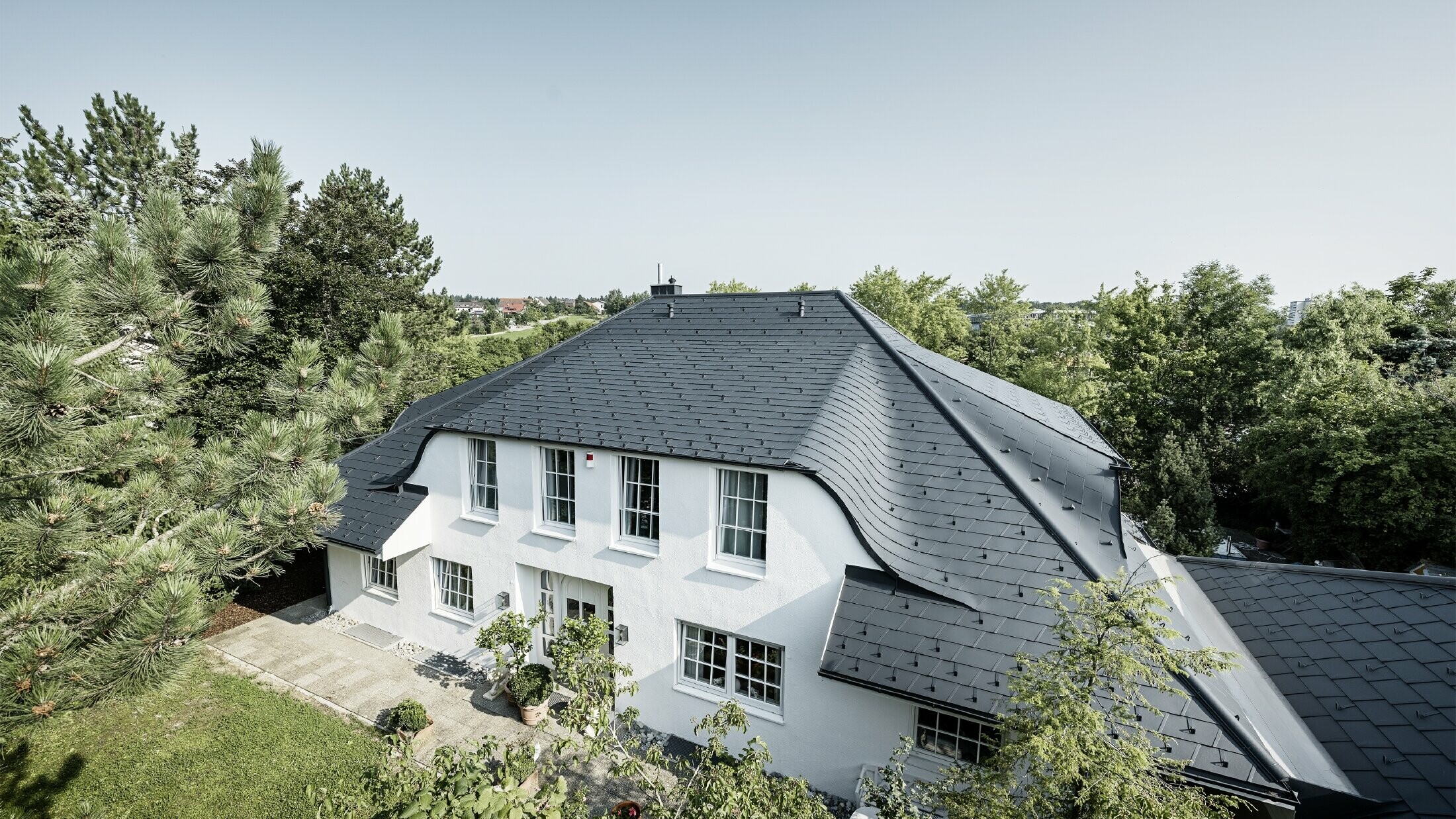 Dach czterospadowy z łukowatymi lukarnami, pokryty aluminiową dachówką łupkową DS.19 w kolorze antracytowym