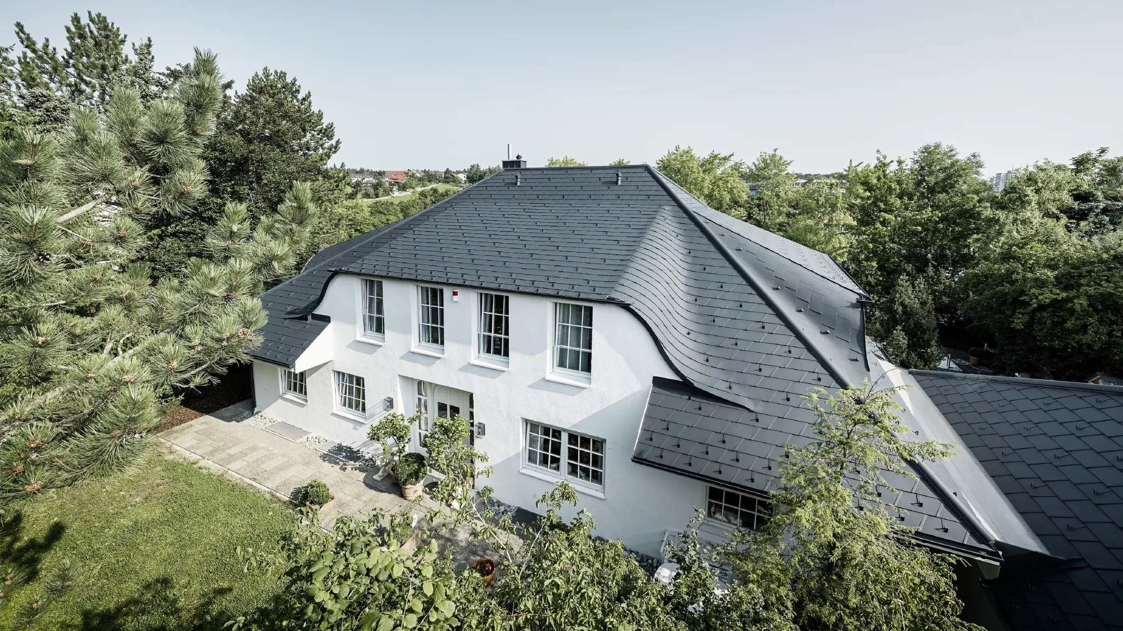 Dach czterospadowy z łukowatymi lukarnami, pokryty aluminiową dachówką łupkową DS.19 w kolorze antracytowym