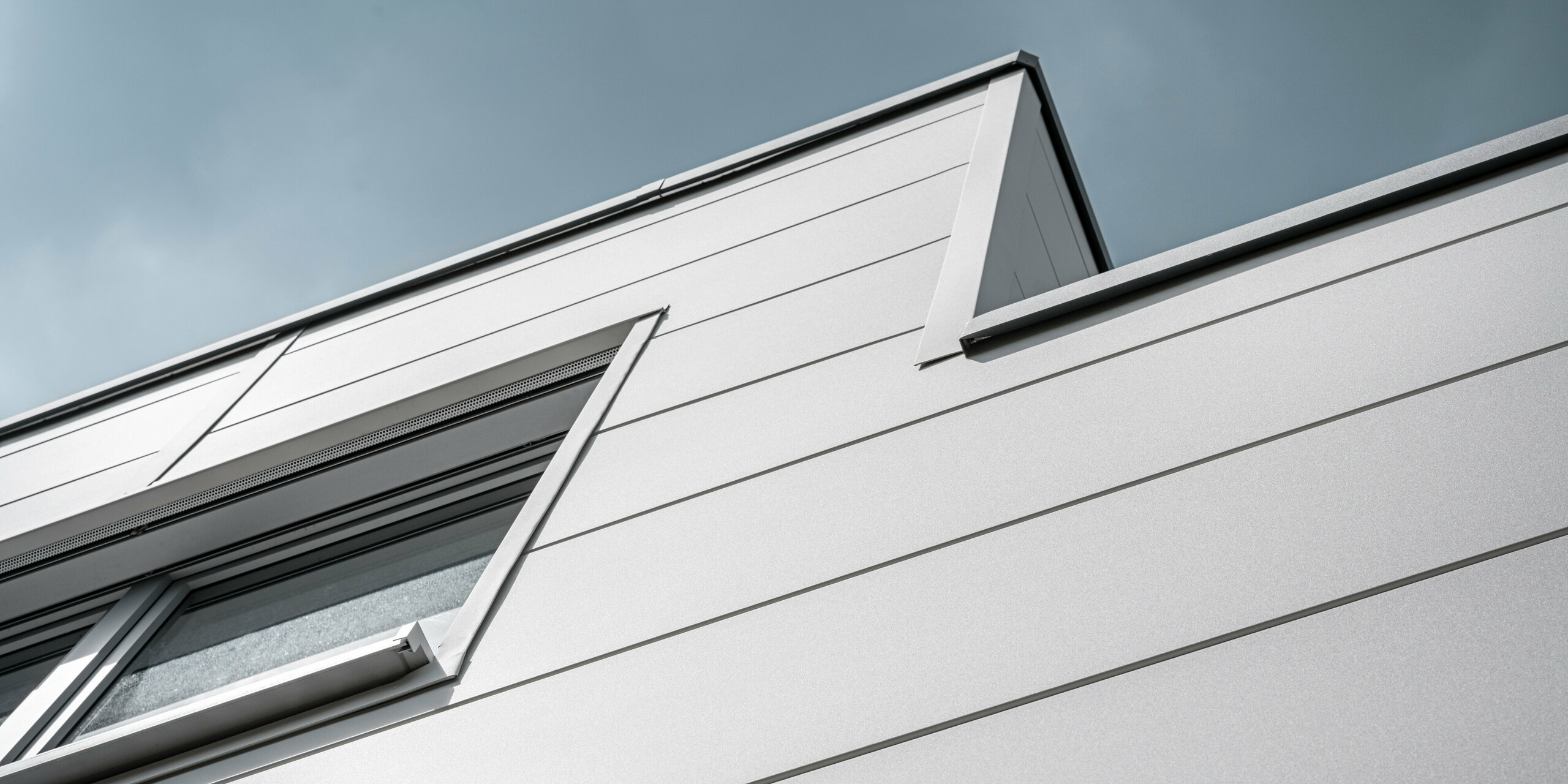Großformatige PREFA Sidings umhüllen ein Firmengebäude in Oberschleißheim (Deutschland). Die extrabreiten Fassadenelemente aus Aluminium sind in der Farbe Prefaweiß gehalten.