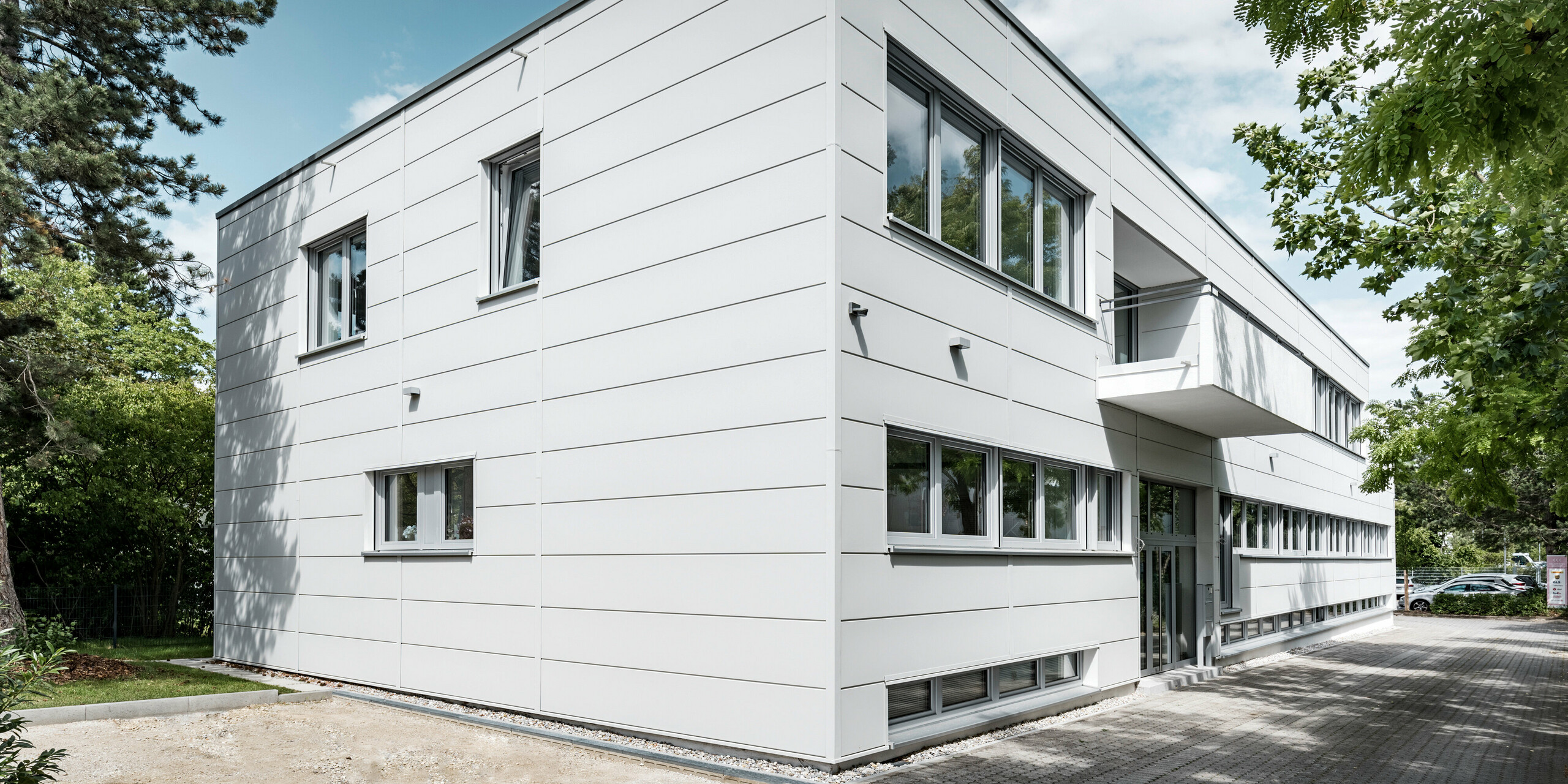 Großformatige PREFA Sidings umhüllen ein Firmengebäude in Oberschleißheim (Deutschland). Die extrabreiten Fassadenelemente aus Aluminium sind in der Farbe Prefaweiß gehalten.