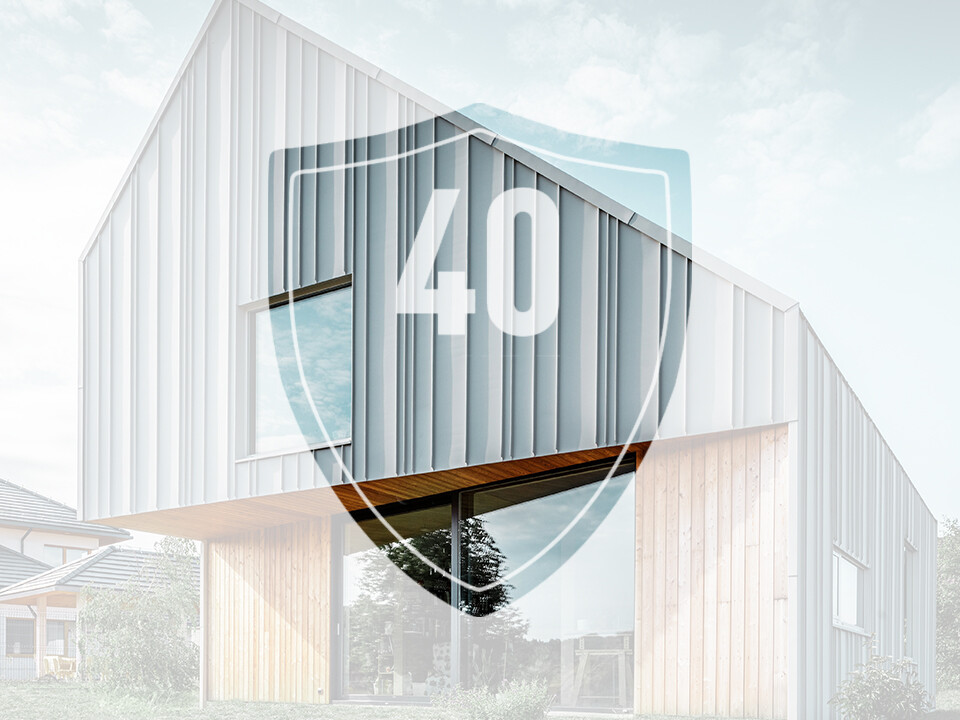 Zdjęcie przedstawia znak z liczbą „40”, który ma reprezentować gwarancję na produkty aluminiowe PREFA, przed nowoczesnym domem jednorodzinnym.