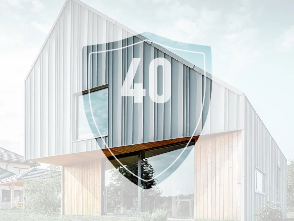 Zdjęcie przedstawia znak z liczbą „40”, który ma reprezentować gwarancję na produkty aluminiowe PREFA, przed nowoczesnym domem jednorodzinnym.