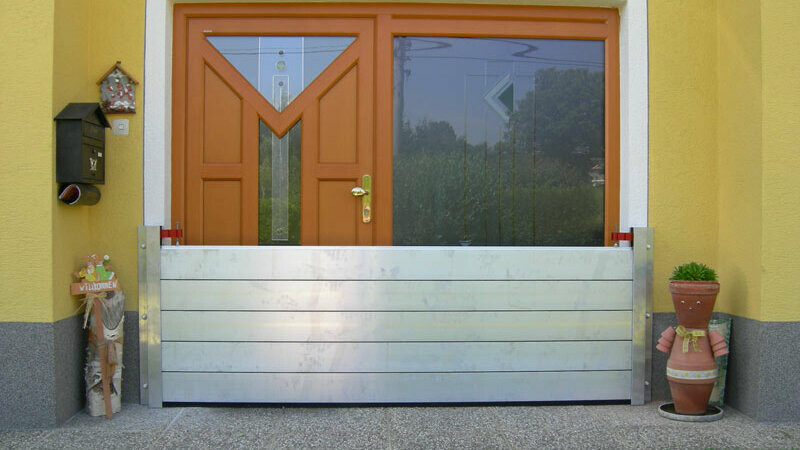 Drzwi wejściowe do domu jednorodzinnego z nowoczesnym systemem ochrony przeciwpowodziowej PREFA 