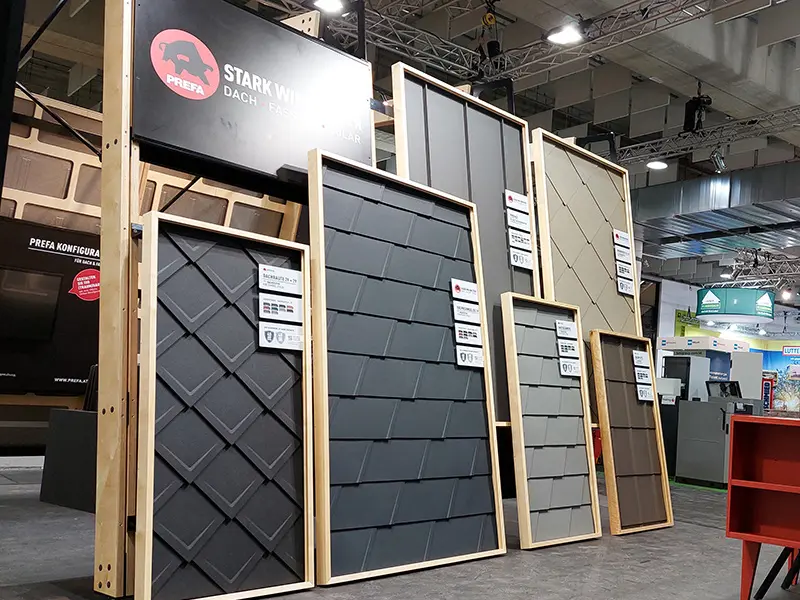 PREFA Messestand mit Messeaufstellern mit verlegten PREFA Aluminiumprodukten zur Ansicht.